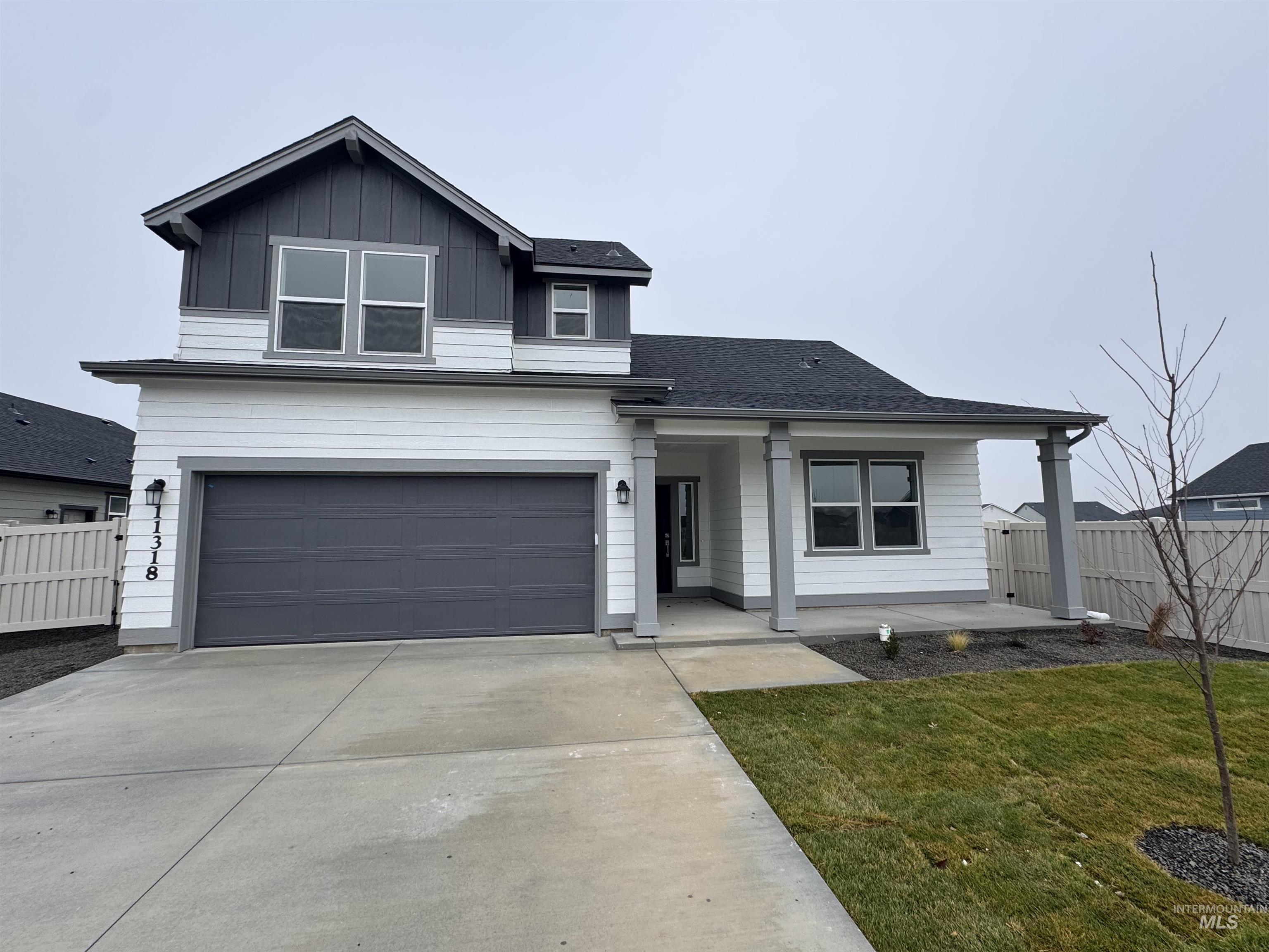 View of front of property with covered porch, concrete driveway, a garage, board and batten siding, and a shingled roof