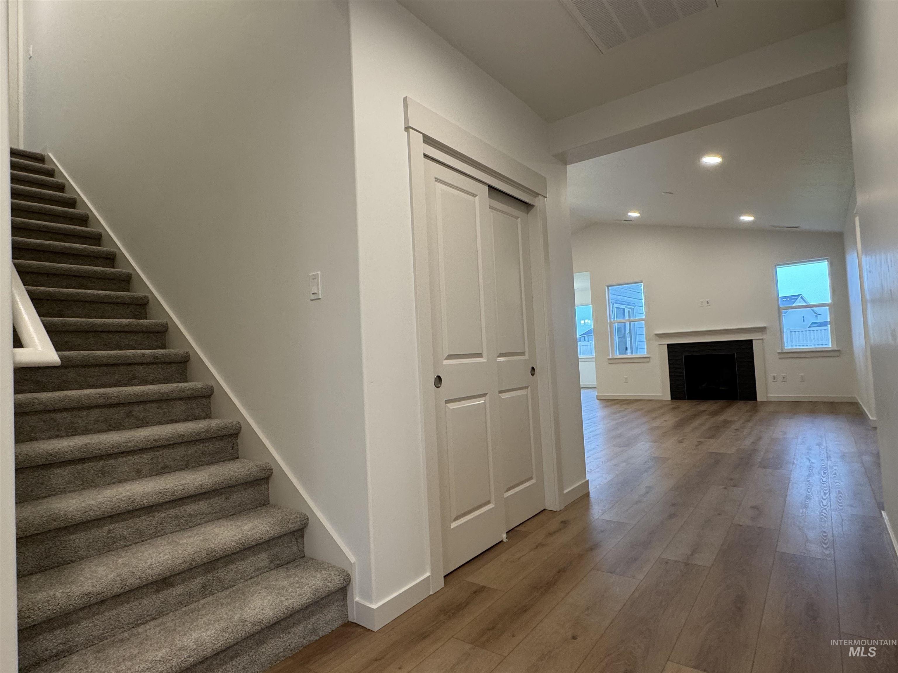 Staircase with recessed lighting, a fireplace, and wood-type flooring