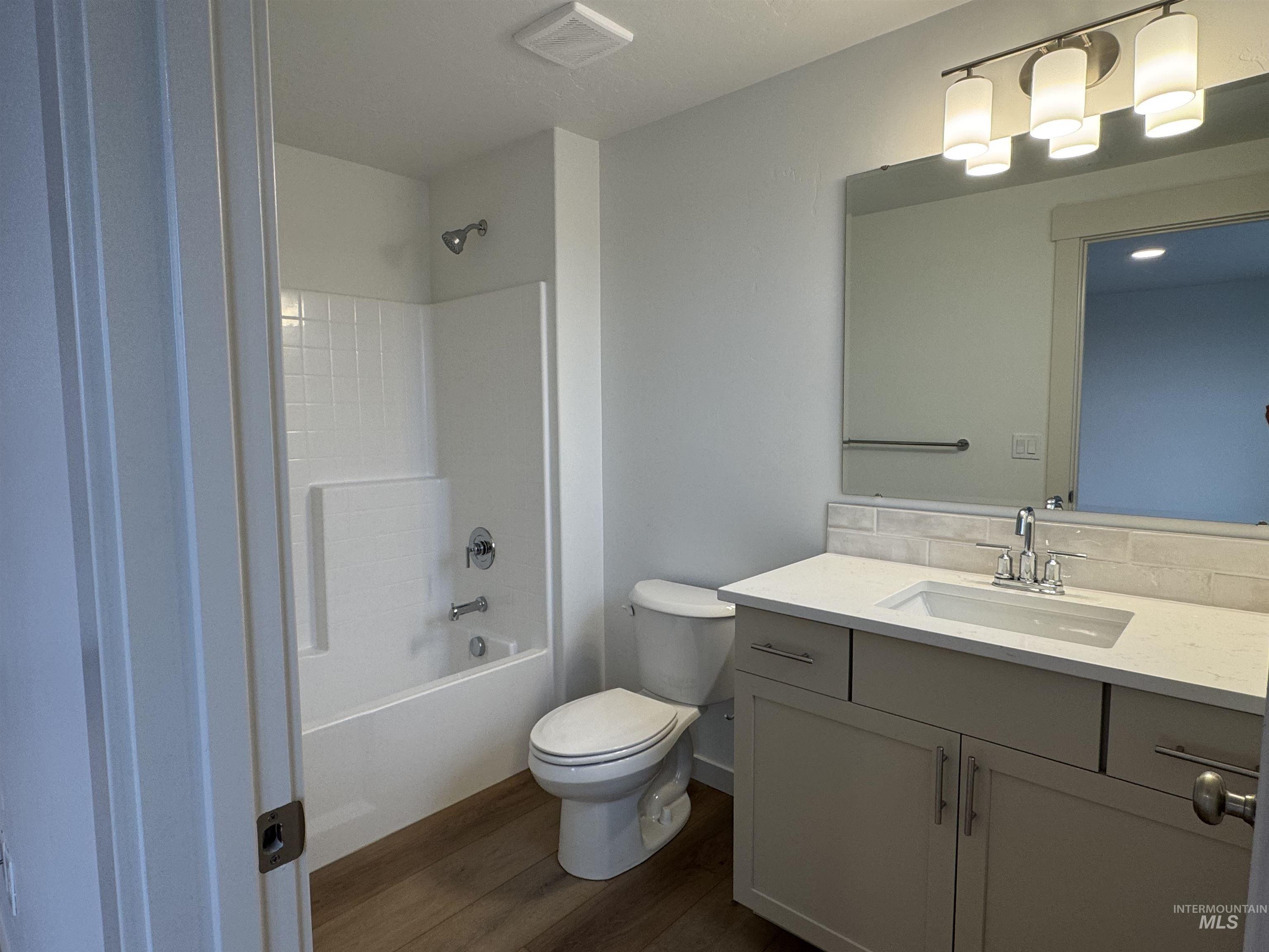 Full bathroom featuring vanity, tub / shower combination, dark wood-type flooring, and decorative backsplash