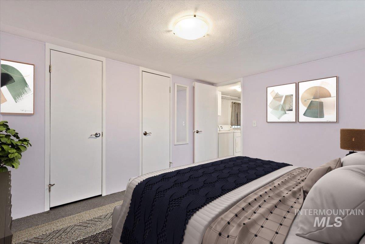 Carpeted bedroom with a textured ceiling and independent washer and dryer