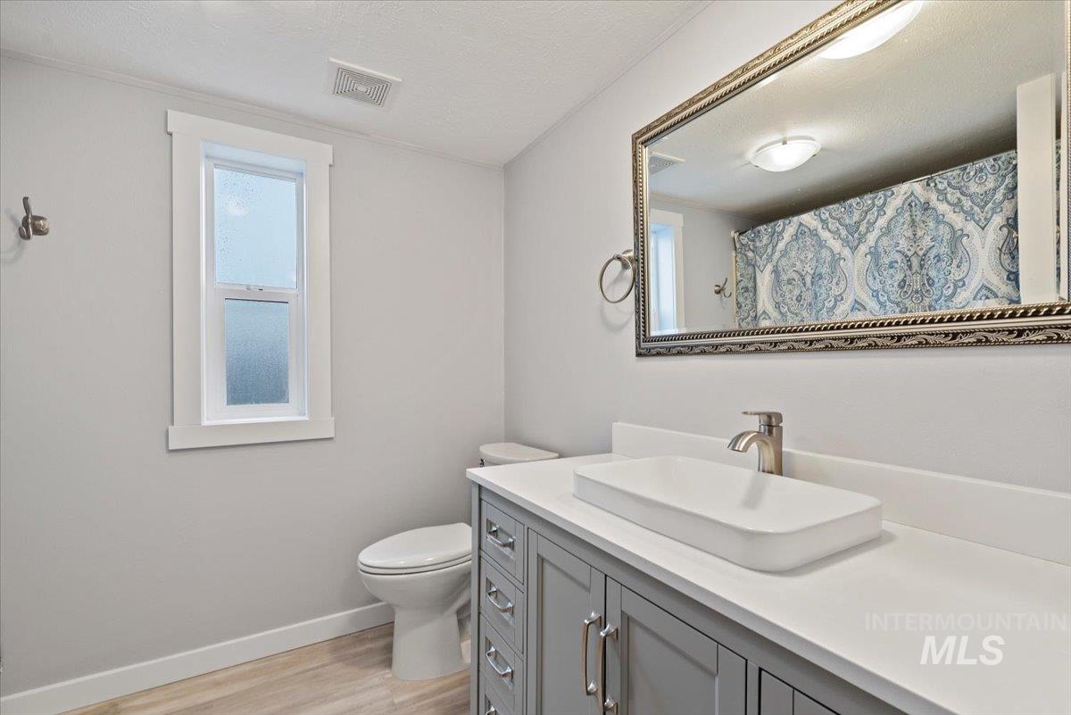 Full bathroom featuring curtained shower, vanity, light wood-style flooring, and a textured ceiling