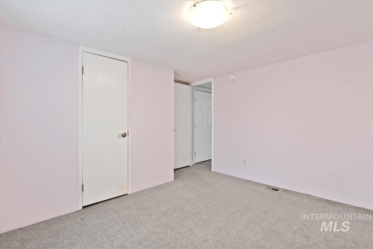 Unfurnished bedroom featuring a textured ceiling, light carpet, and a closet