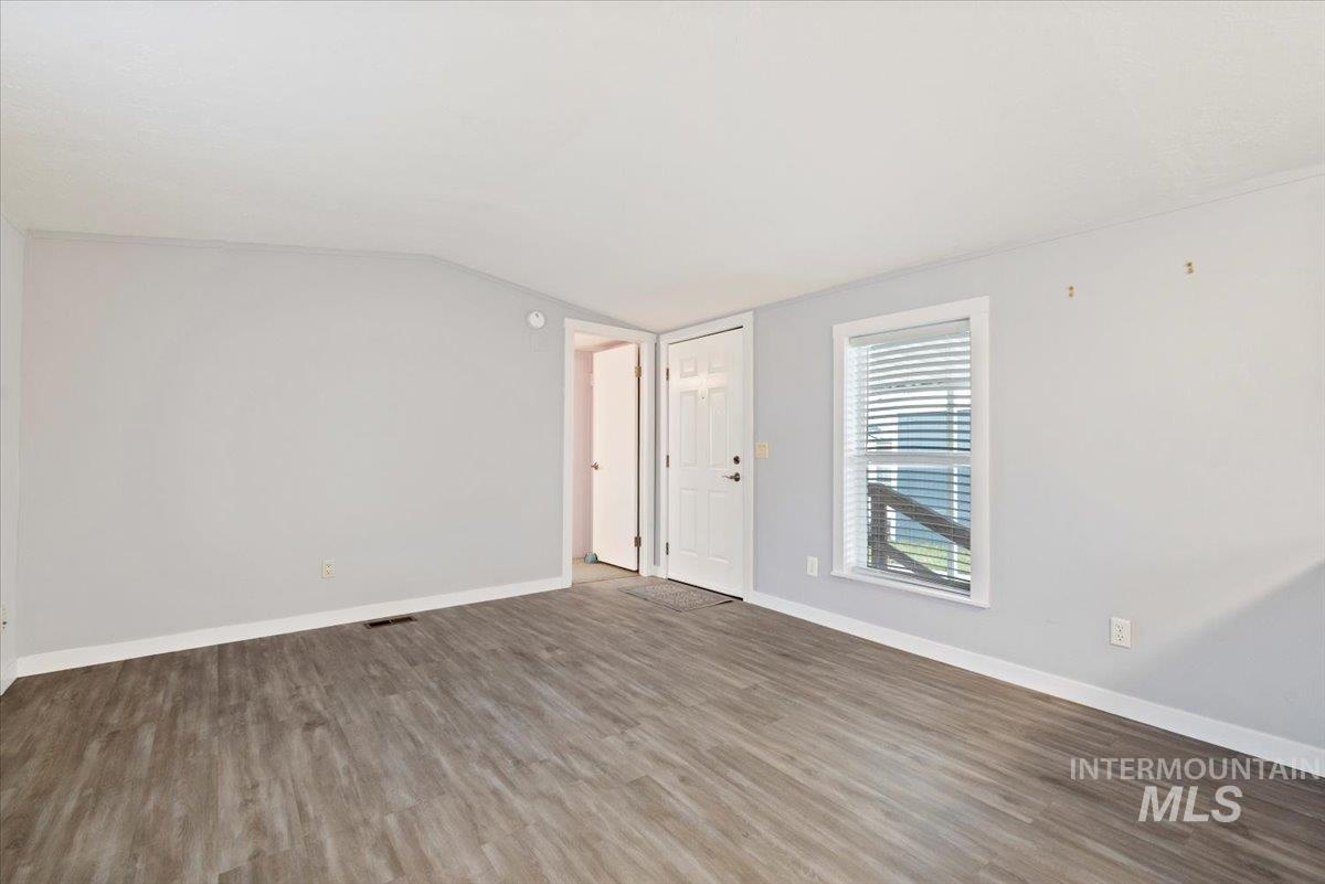 Unfurnished room with vaulted ceiling and wood finished floors