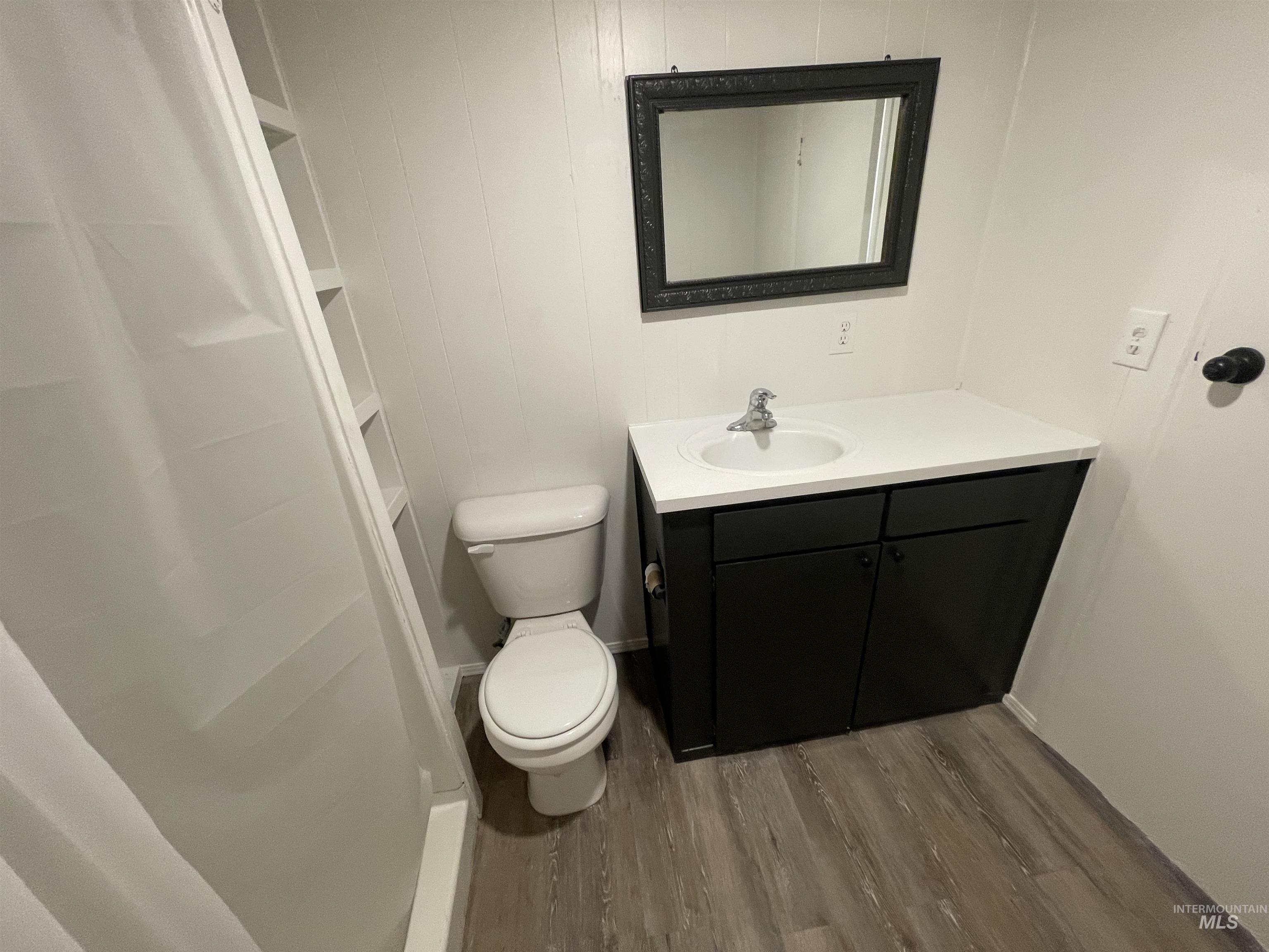 Full bathroom with a shower stall, vanity, and wood finished floors