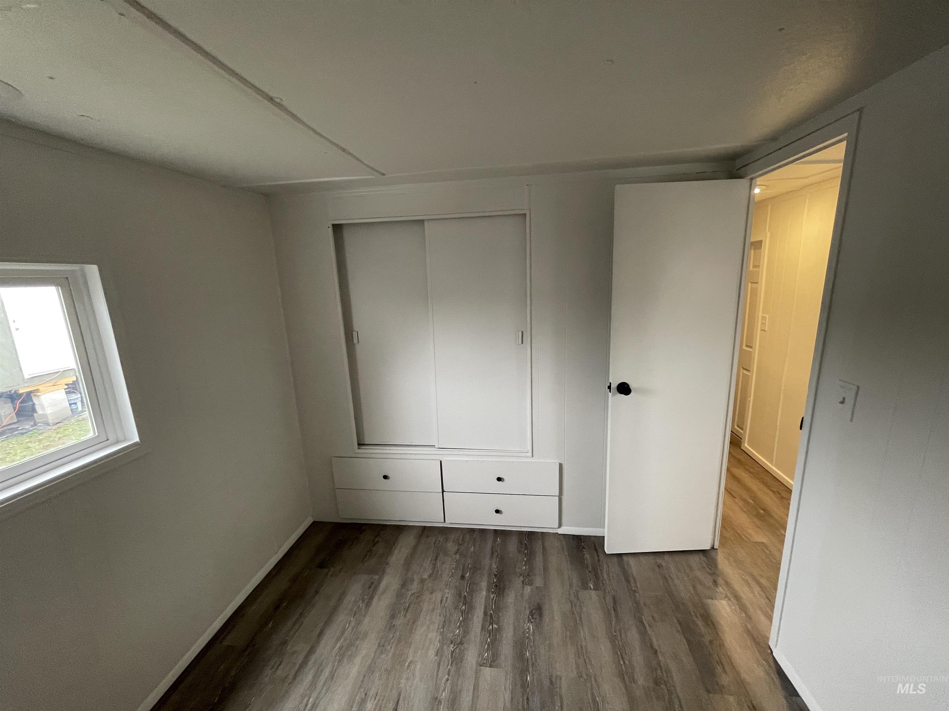 Unfurnished bedroom with dark wood-style flooring and a closet