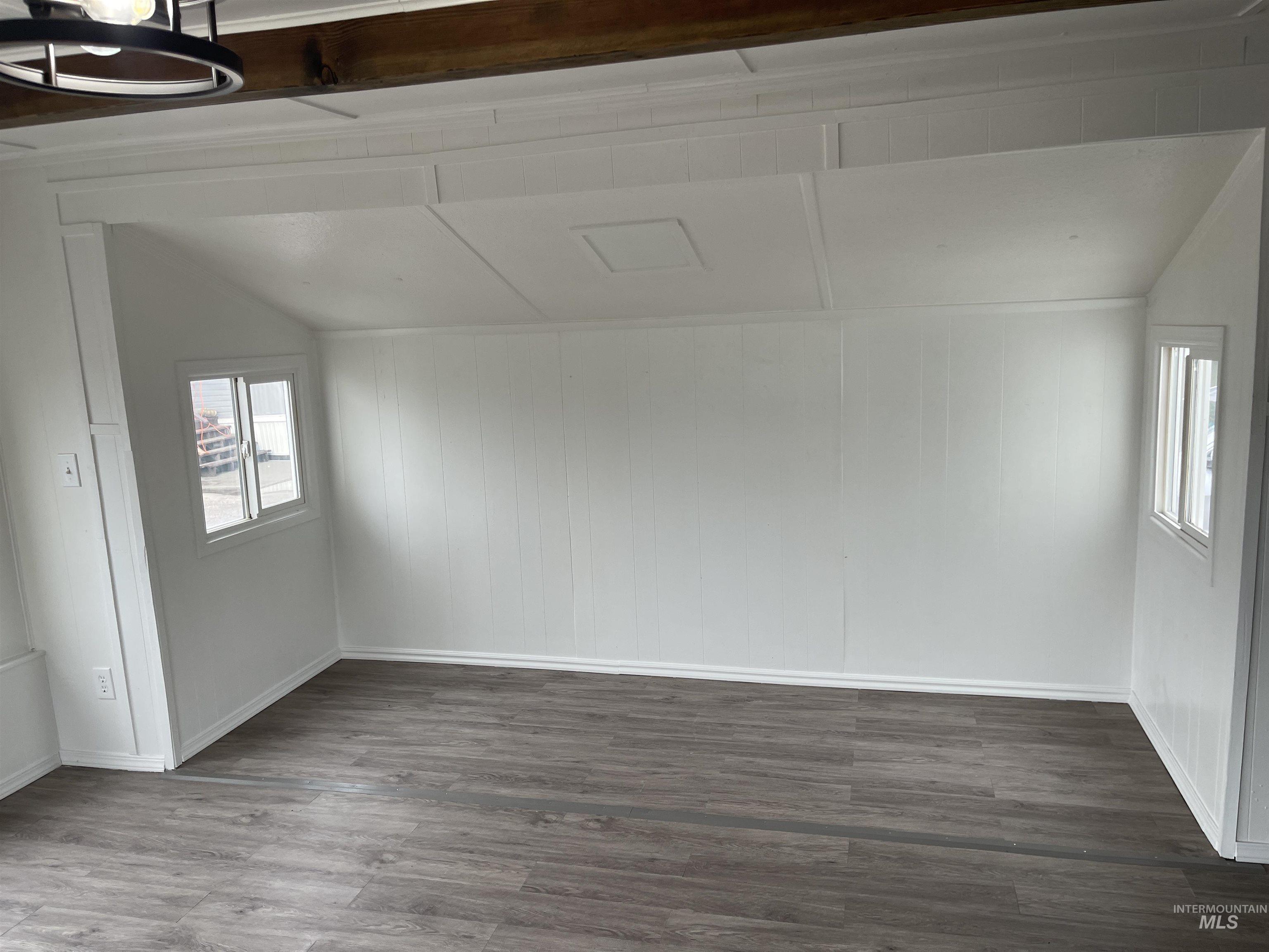 Unfurnished room featuring dark wood-style floors and lofted ceiling