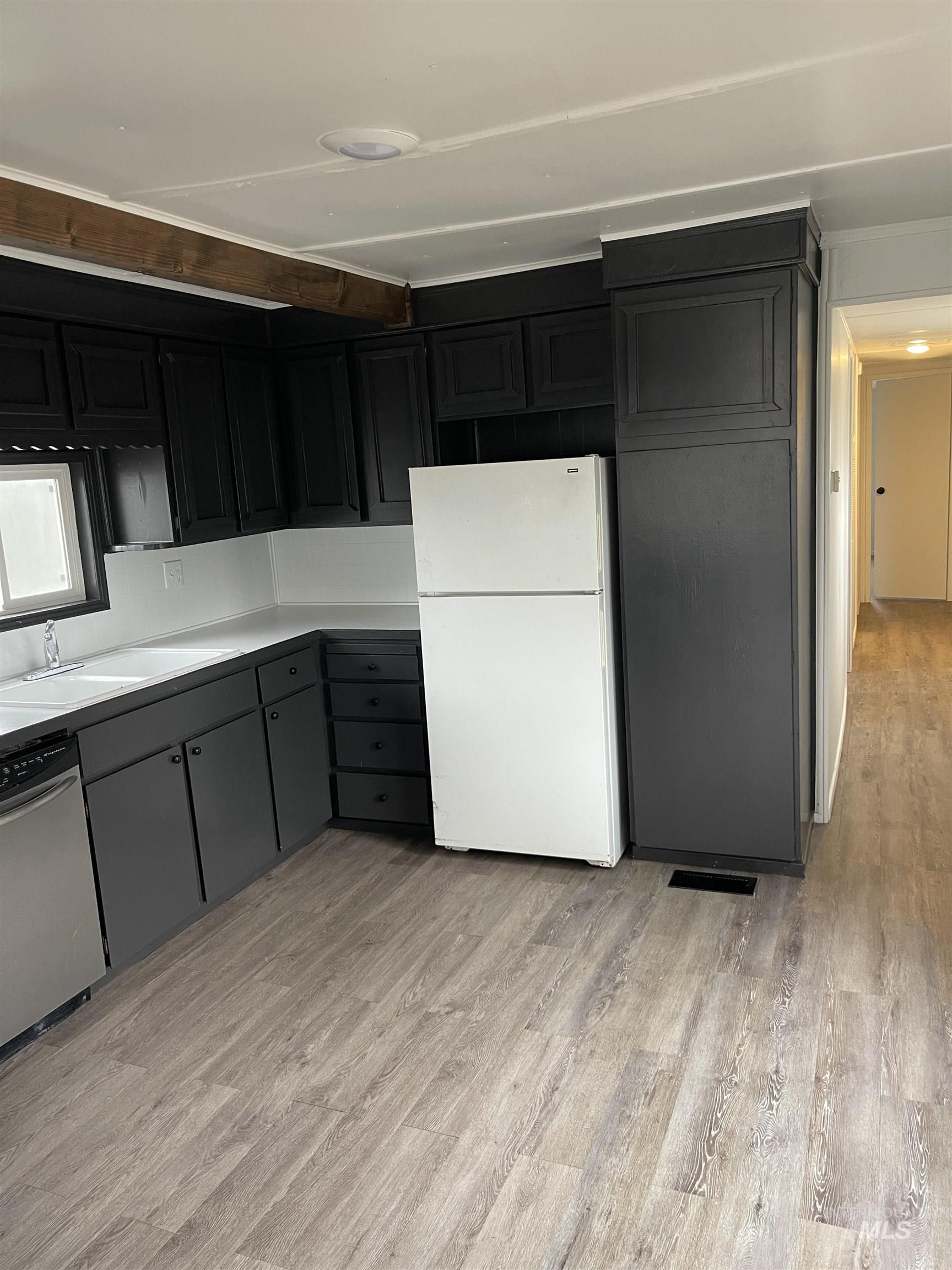 Kitchen with freestanding refrigerator, light countertops, light wood finished floors, dishwasher, and gray cabinetry