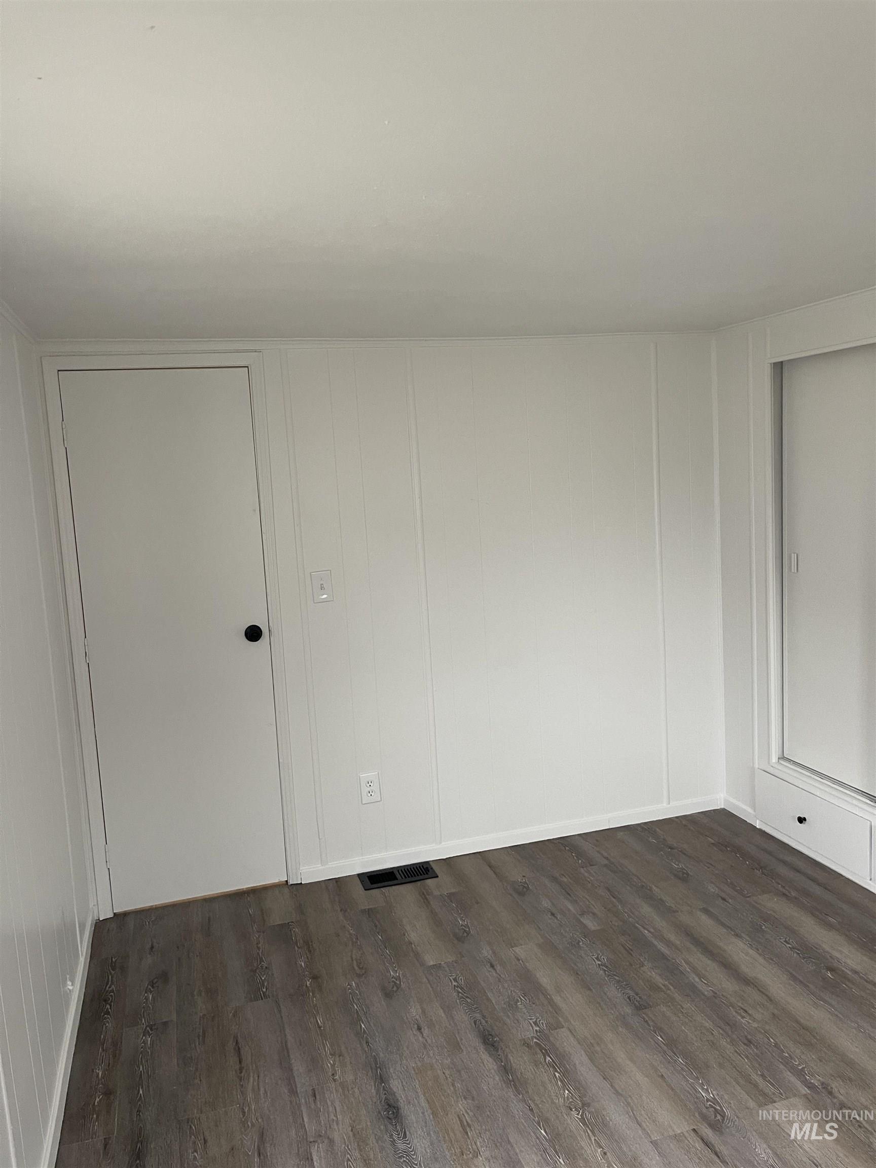 Spare room with dark wood-style flooring and a decorative wall