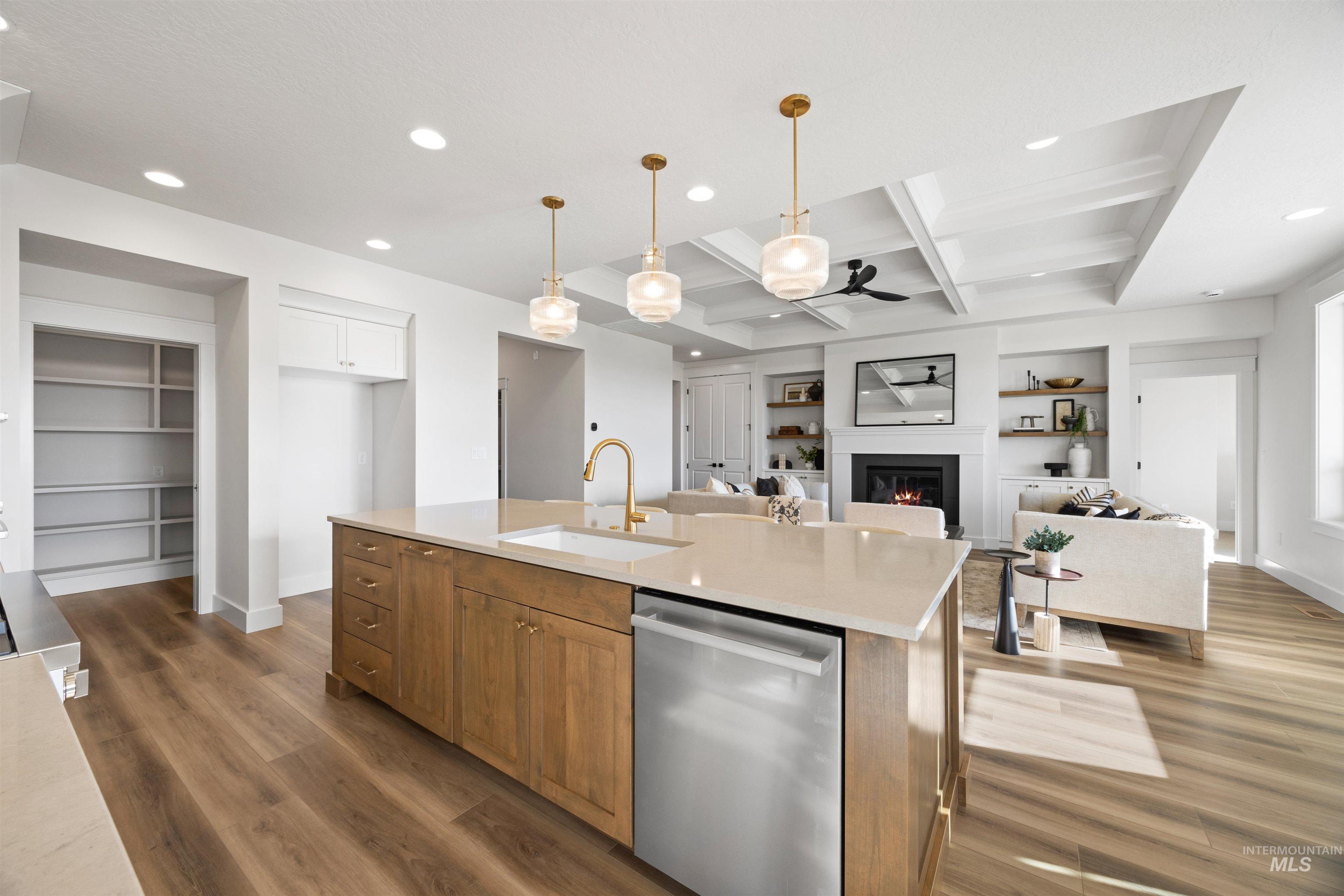Kitchen featuring built in features, brown cabinetry, a glass covered fireplace, dishwasher, and coffered ceiling