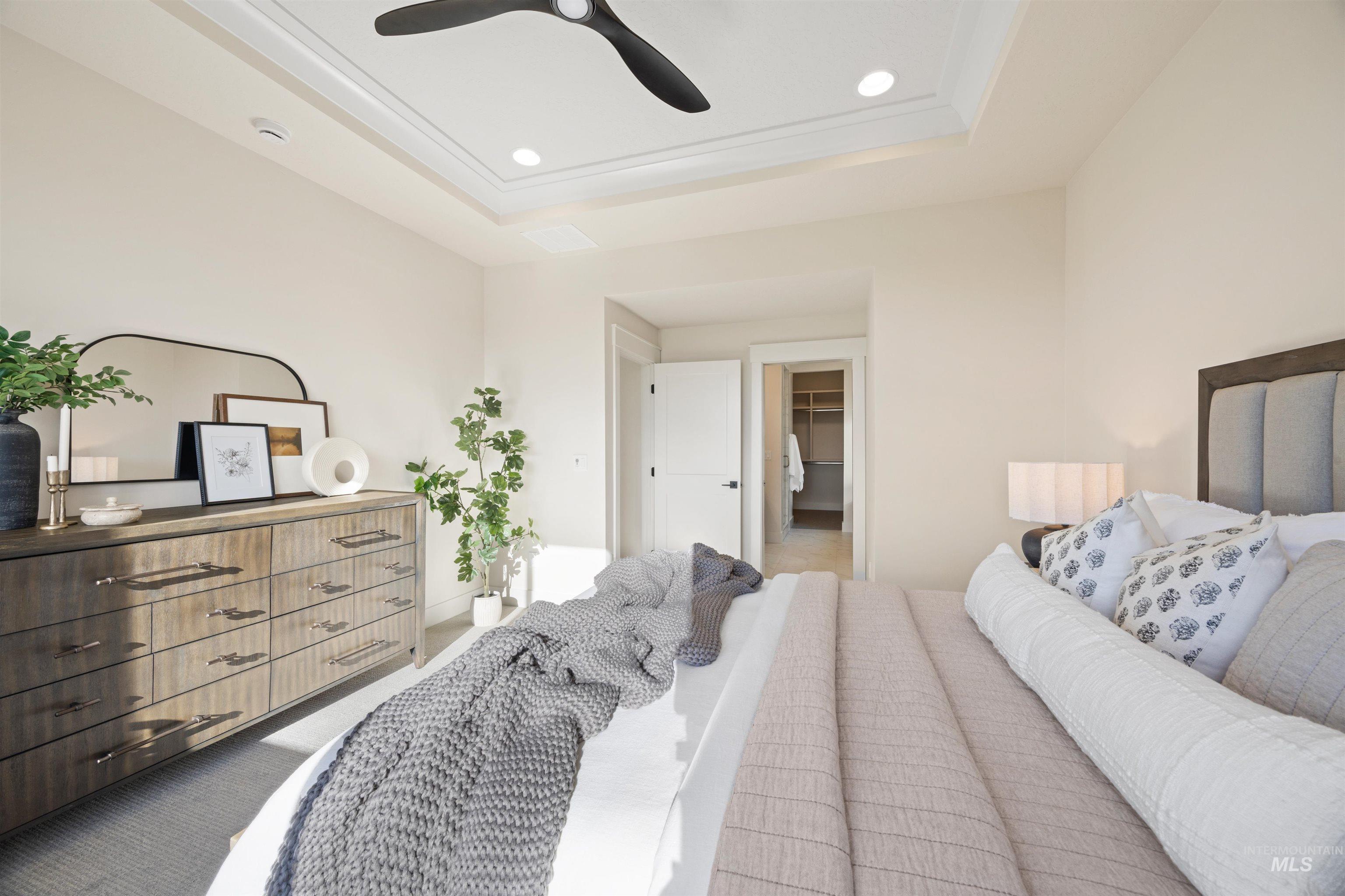 Bedroom with carpet floors, a spacious closet, a tray ceiling, ceiling fan, and recessed lighting