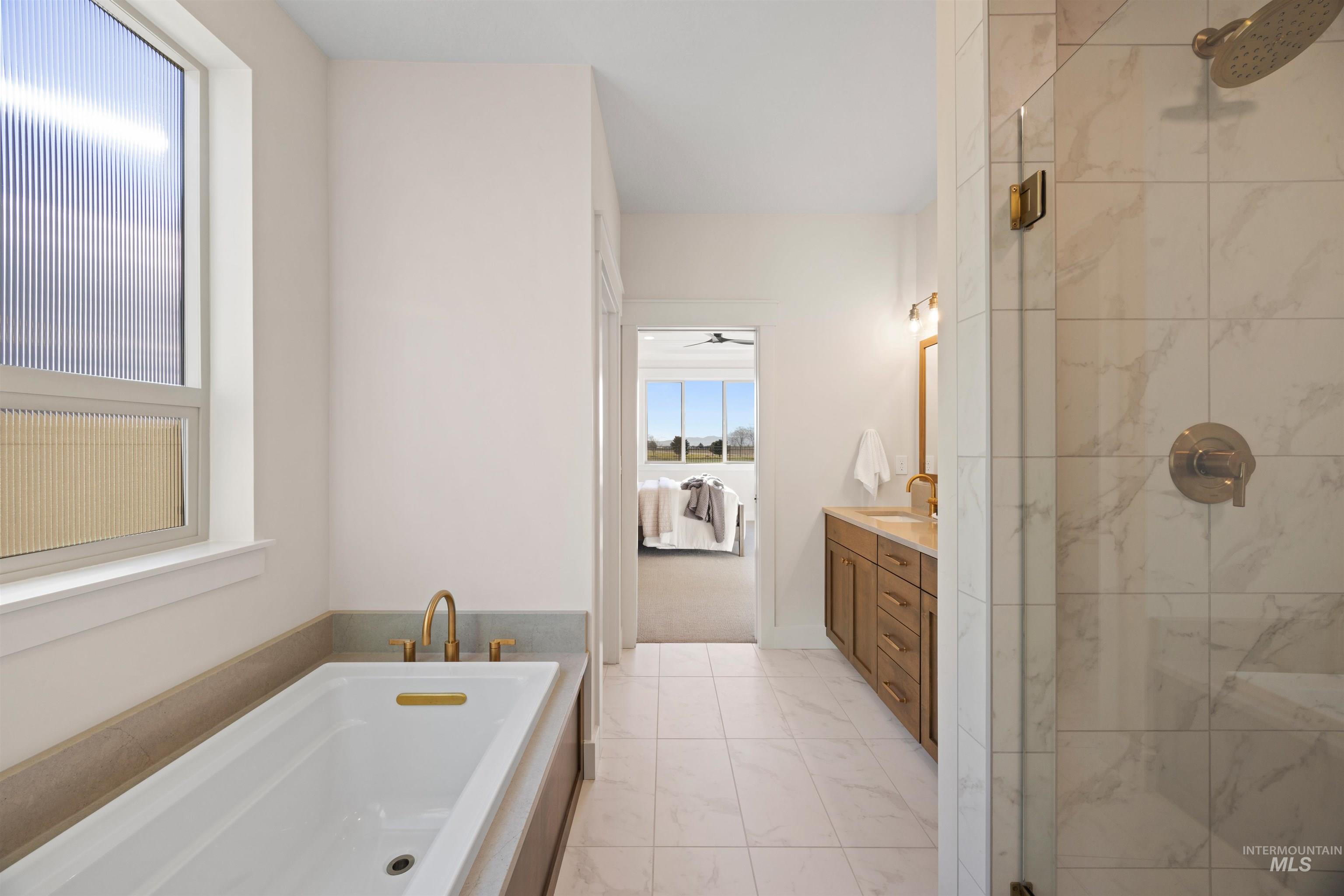 Ensuite bathroom with a bath, vanity, a stall shower, light marble finish floors, and a ceiling fan