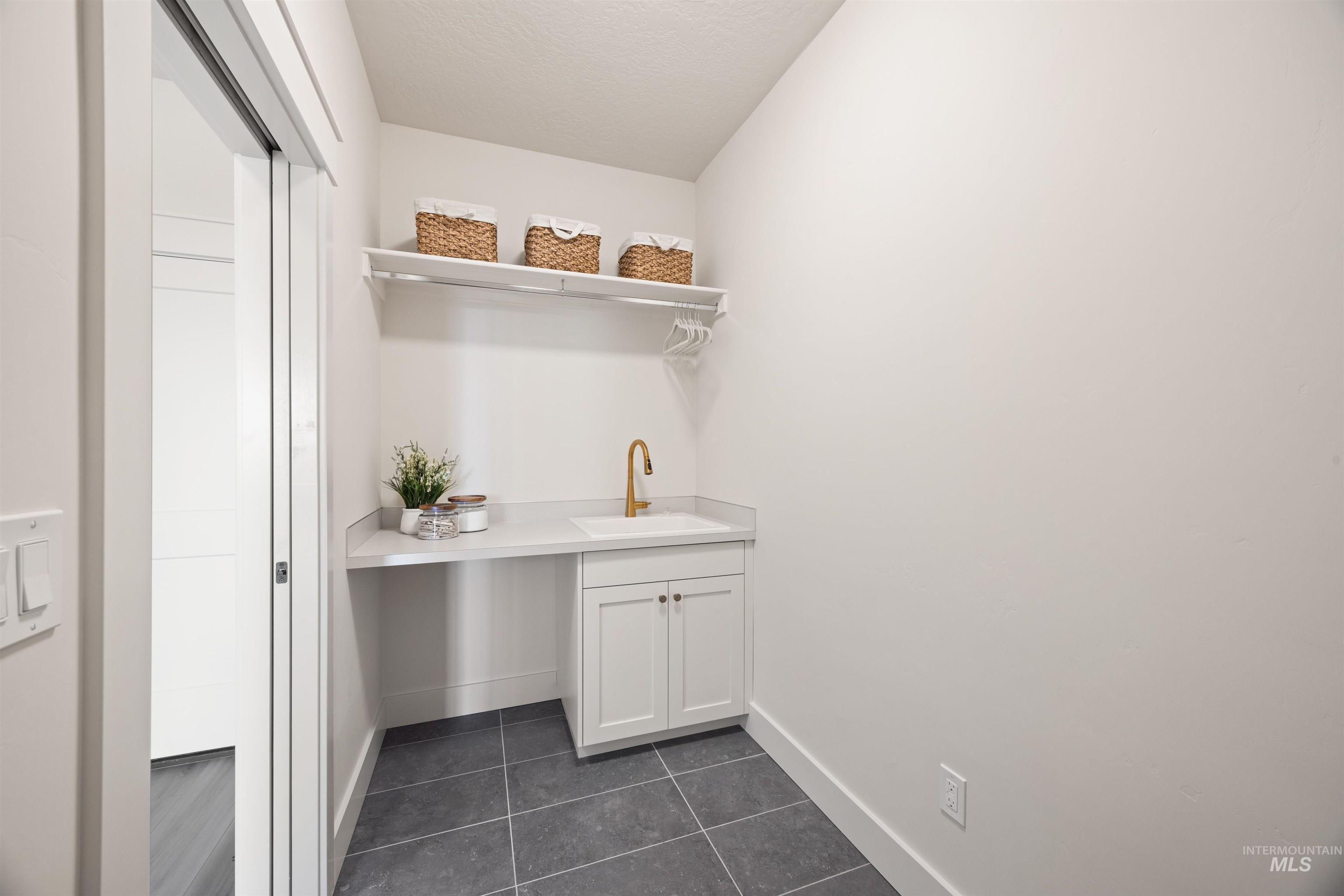 Laundry area with dark tile patterned floors and a textured ceiling