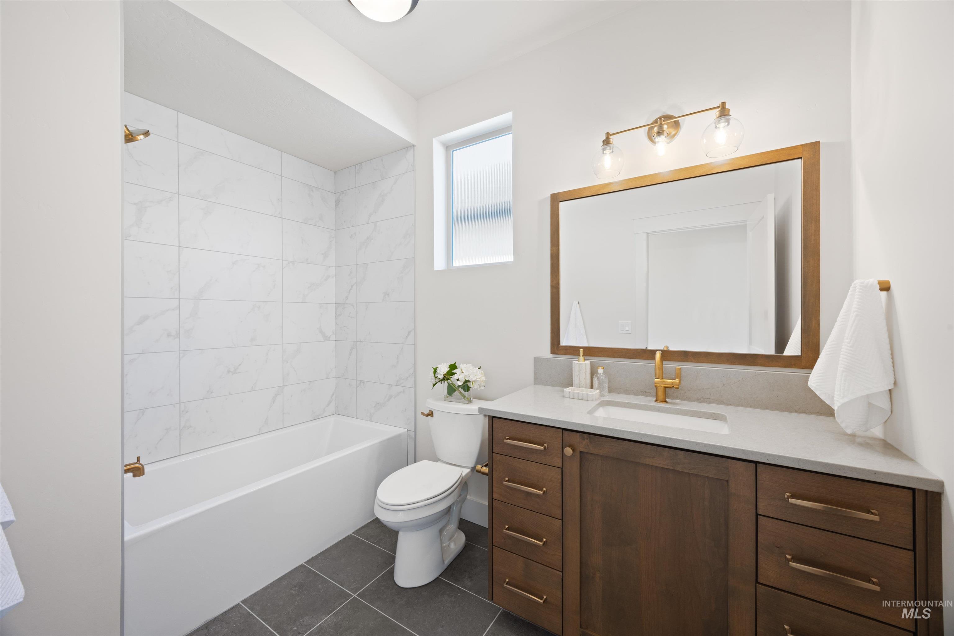 Bathroom featuring bathtub / shower combination, vanity, and dark tile patterned floors