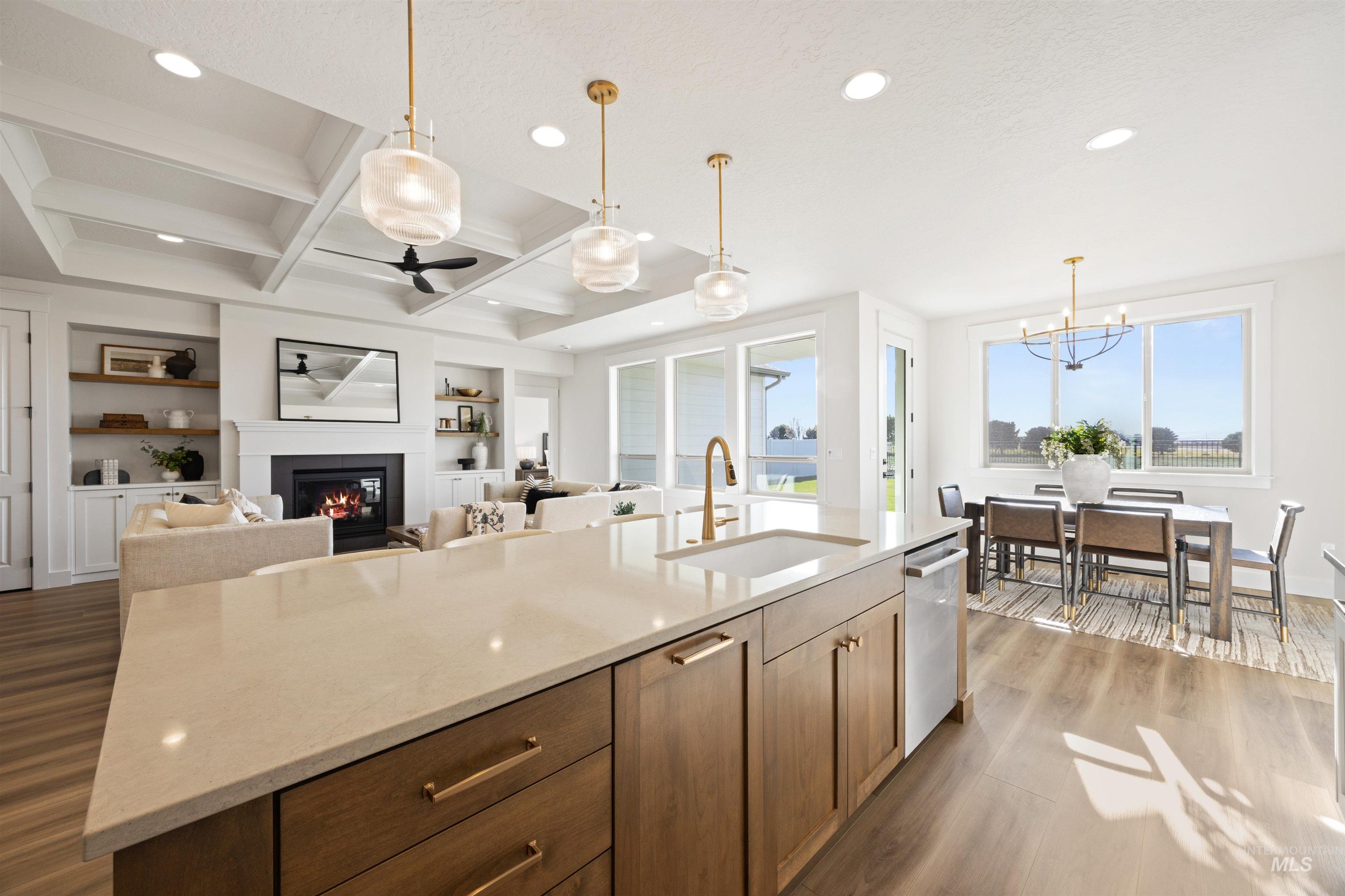 Kitchen with built in features, a glass covered fireplace, light stone counters, coffered ceiling, and pendant lighting