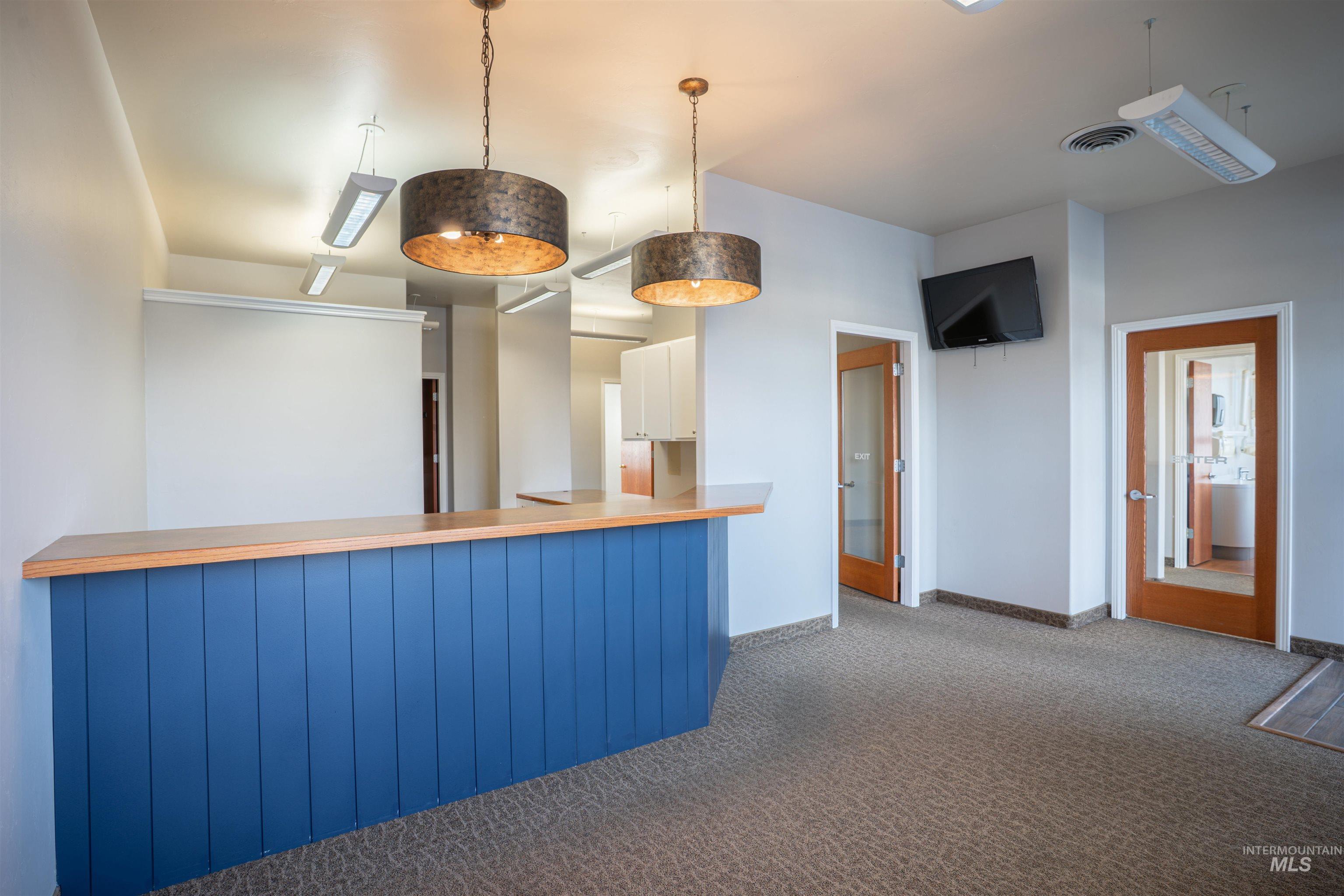 Kitchen with white cabinets, carpet floors, a peninsula, pendant lighting, and light countertops