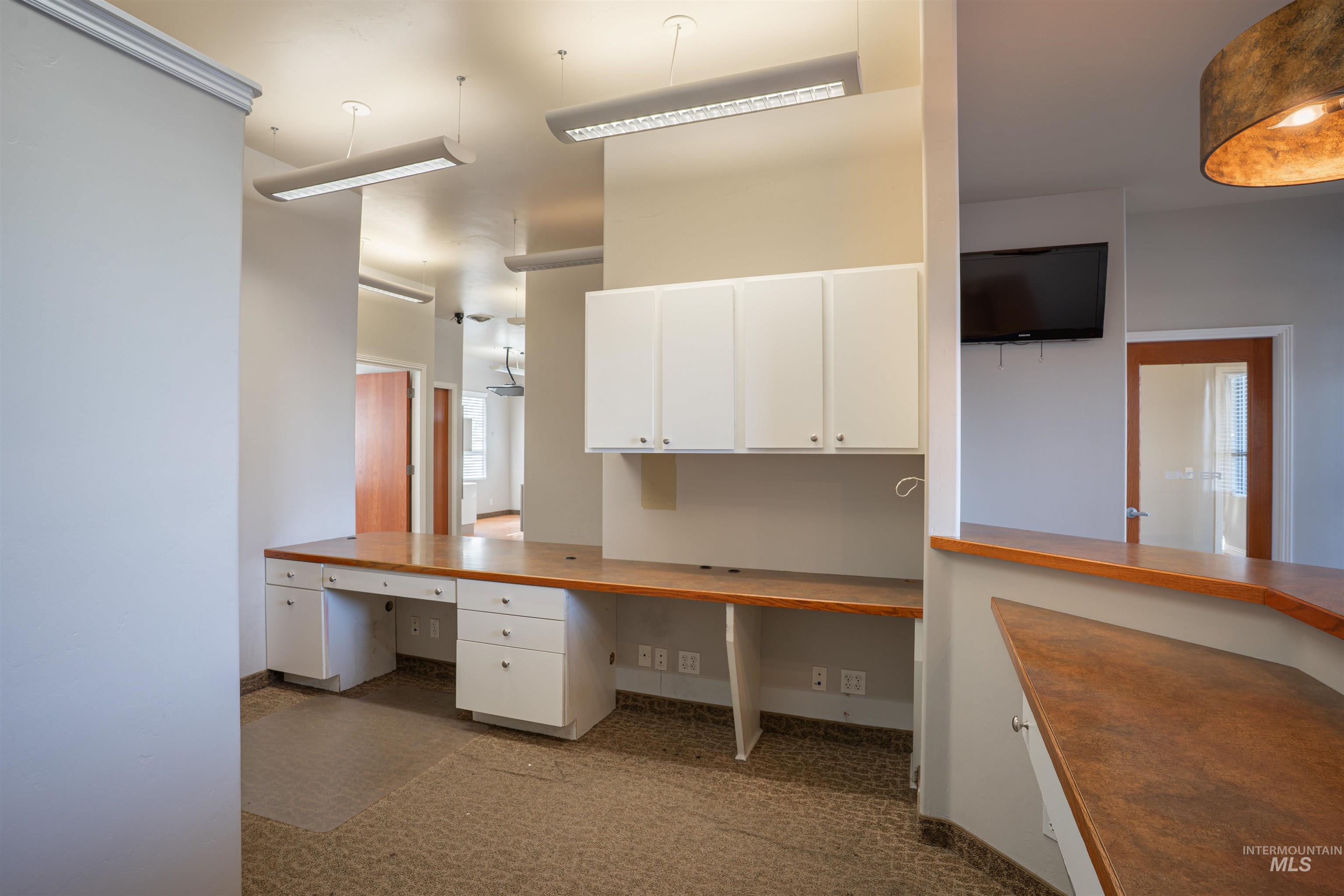 Unfurnished office featuring built in desk and dark colored carpet