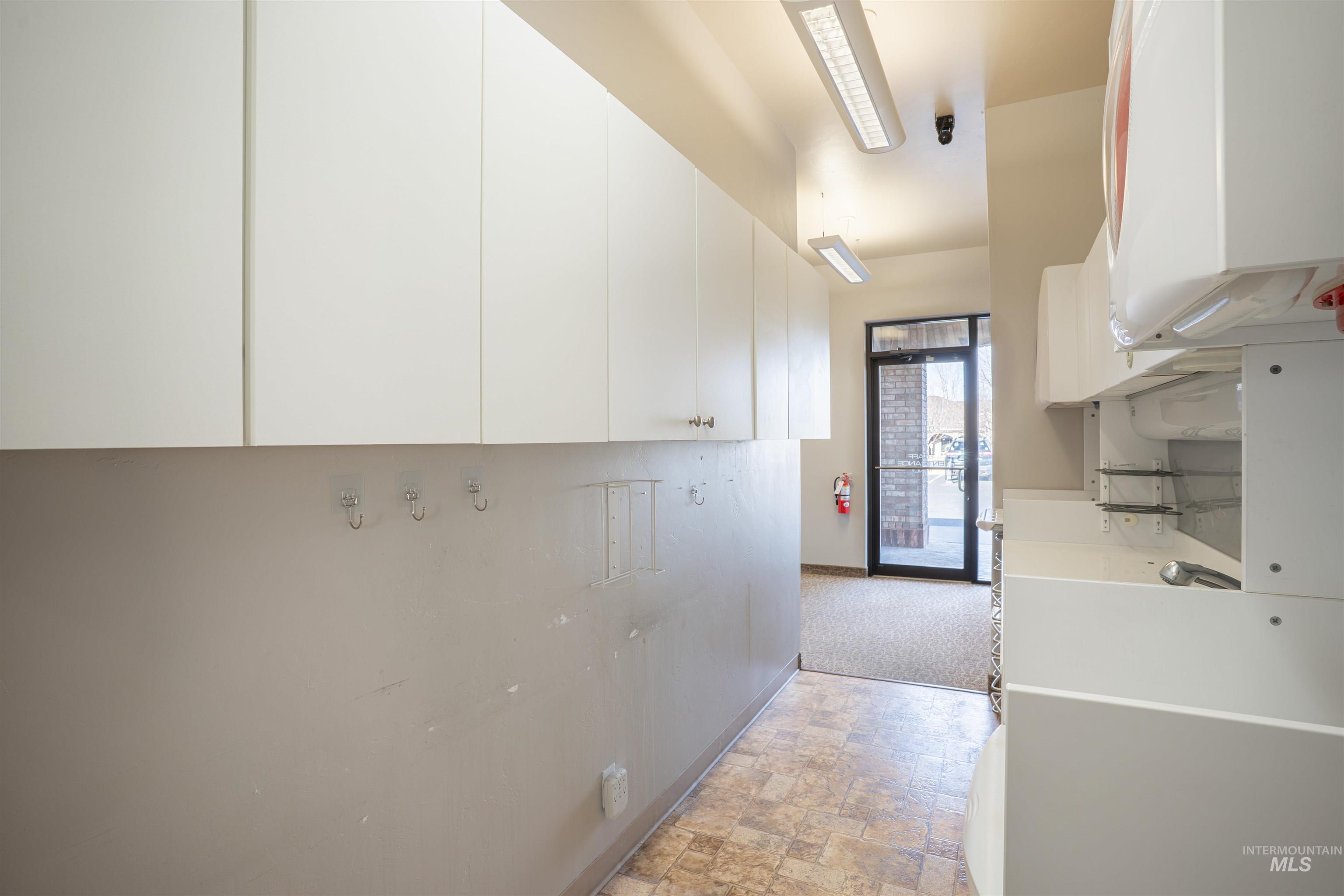 Kitchen featuring stone finish floors, white cabinets, and light countertops