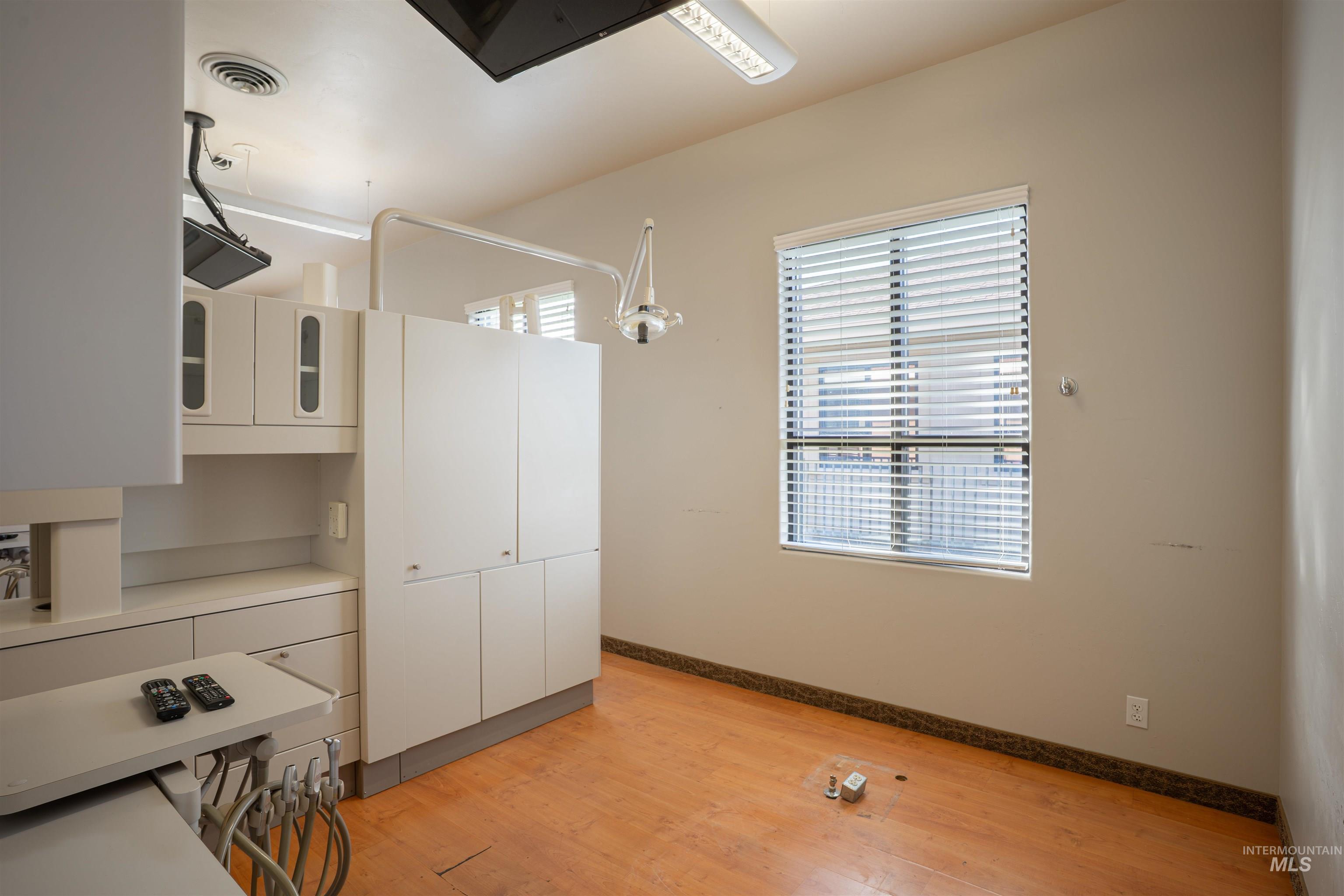 Kitchen with white cabinets, light countertops, light wood-type flooring, hanging light fixtures, and glass insert cabinets