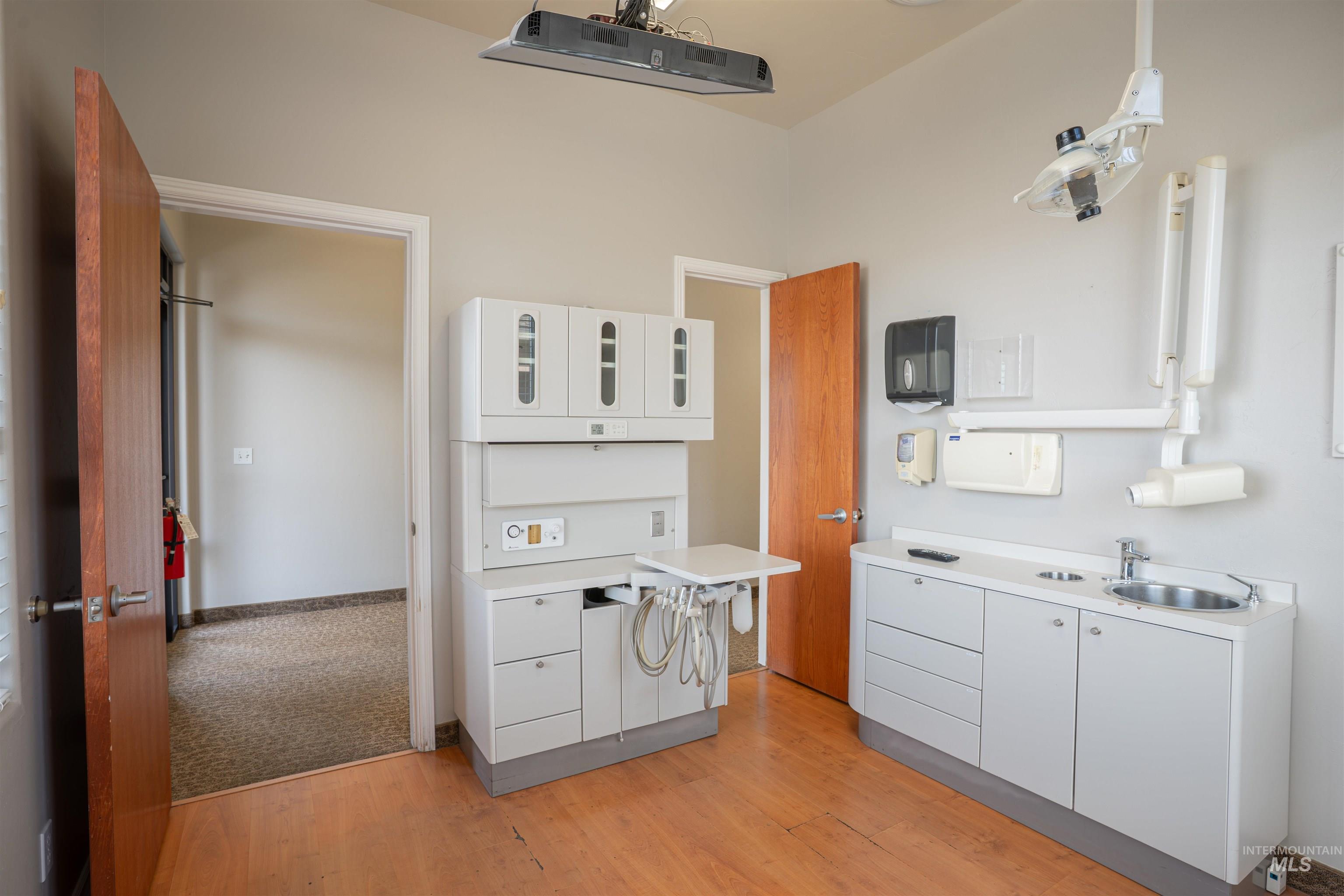 Kitchen featuring white cabinets, light countertops, glass insert cabinets, and light wood finished floors