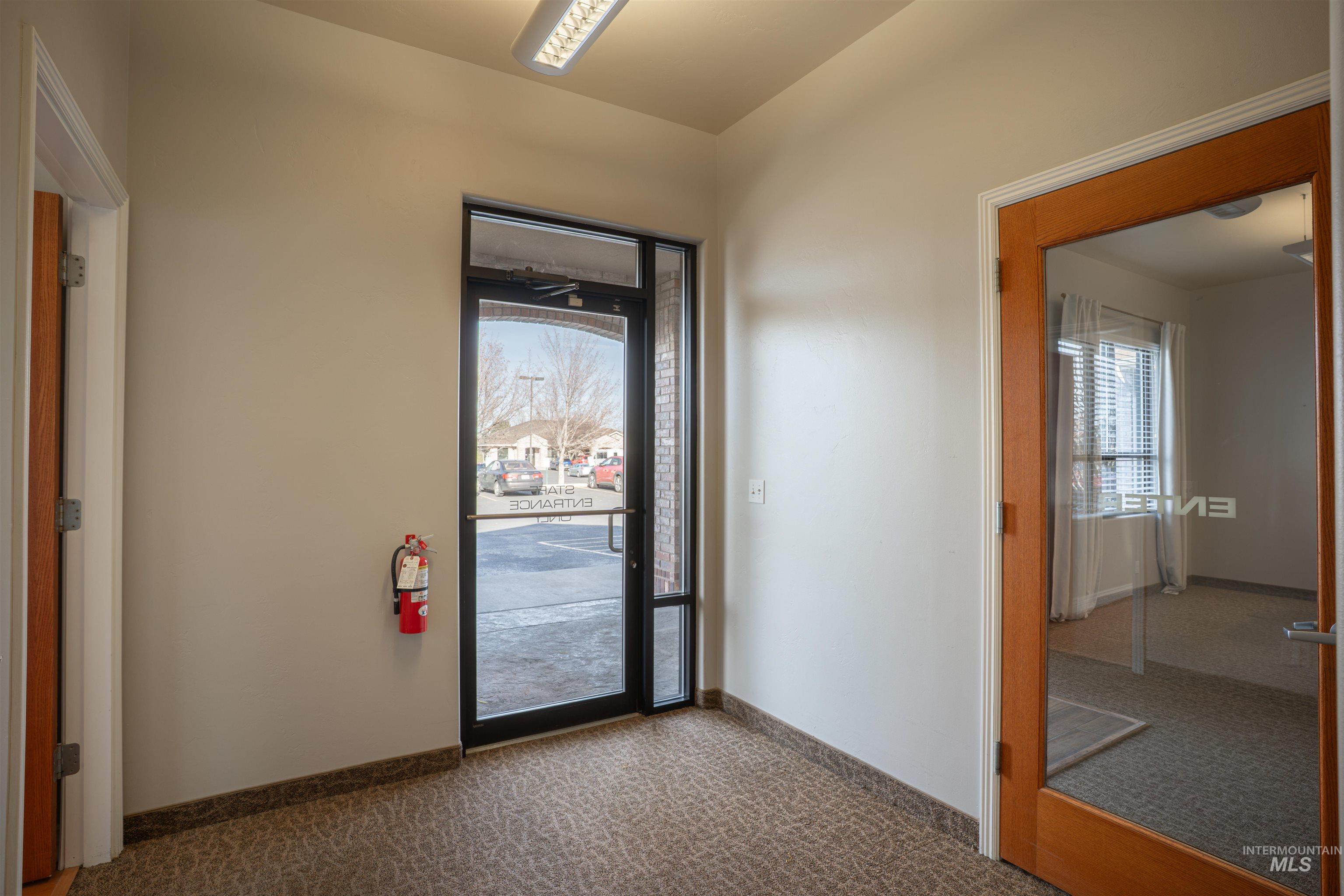 Doorway featuring carpet flooring and baseboards