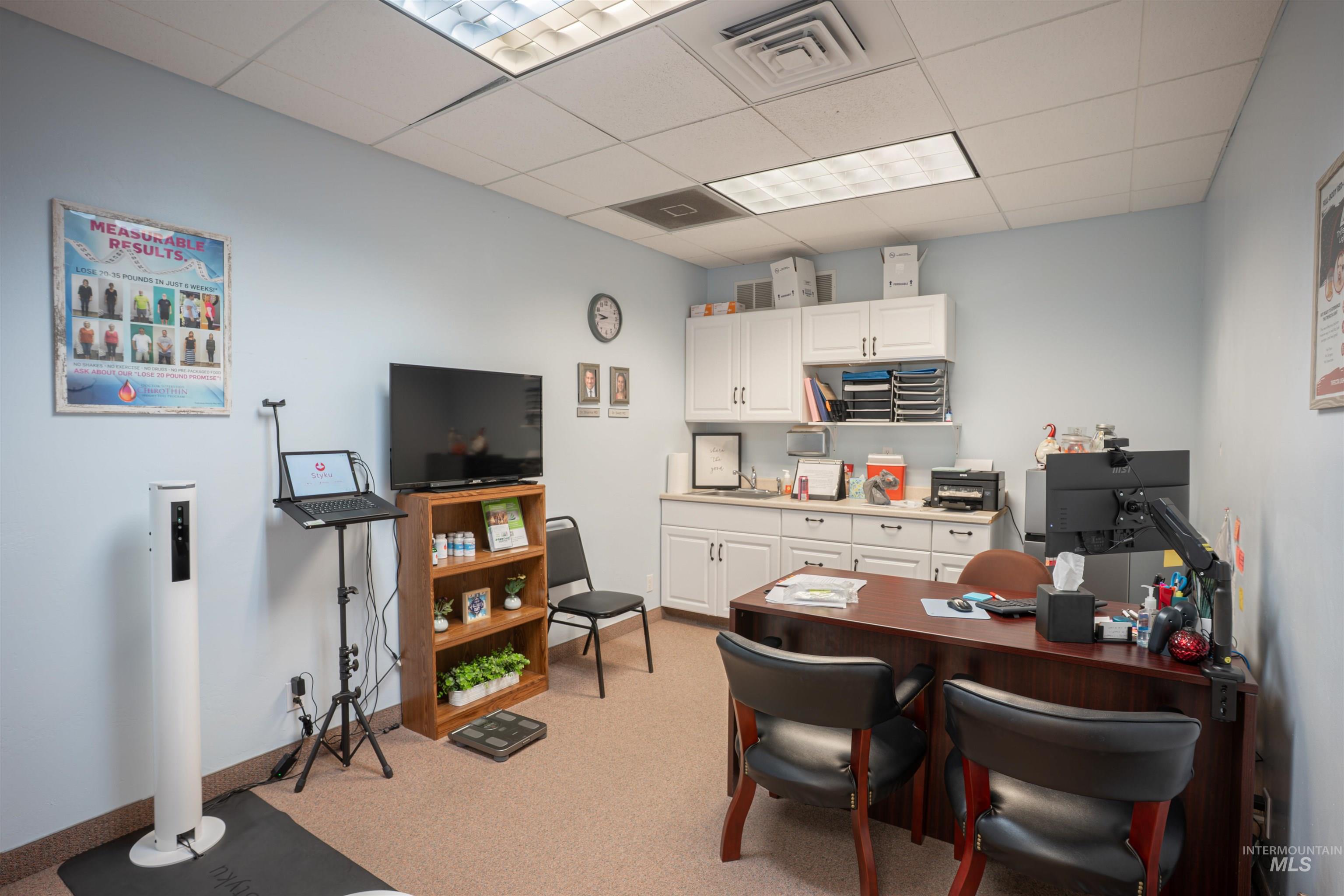 Office with a paneled ceiling and light colored carpet