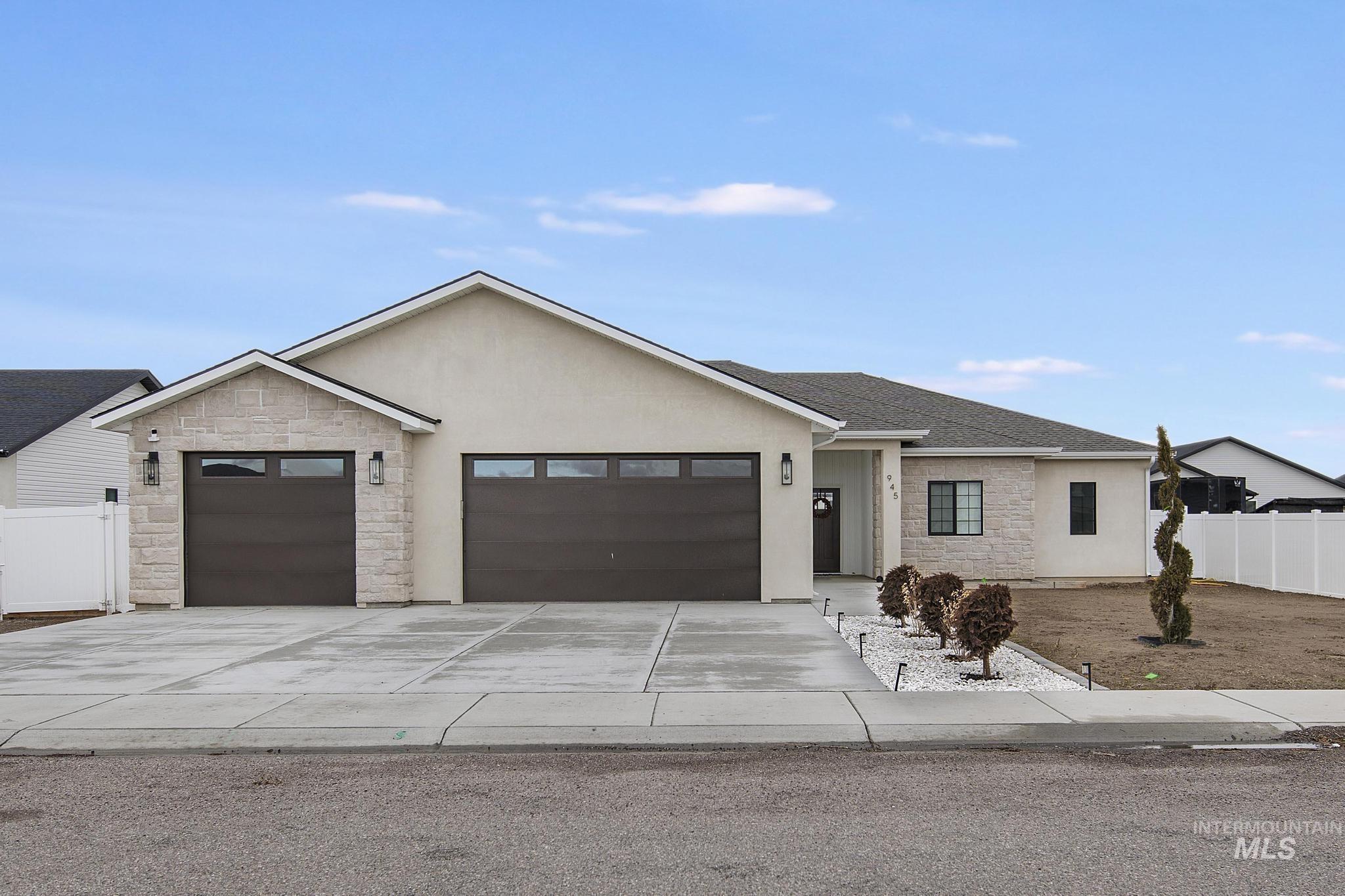 Ranch-style home with stone siding, an attached garage, concrete driveway, and stucco siding