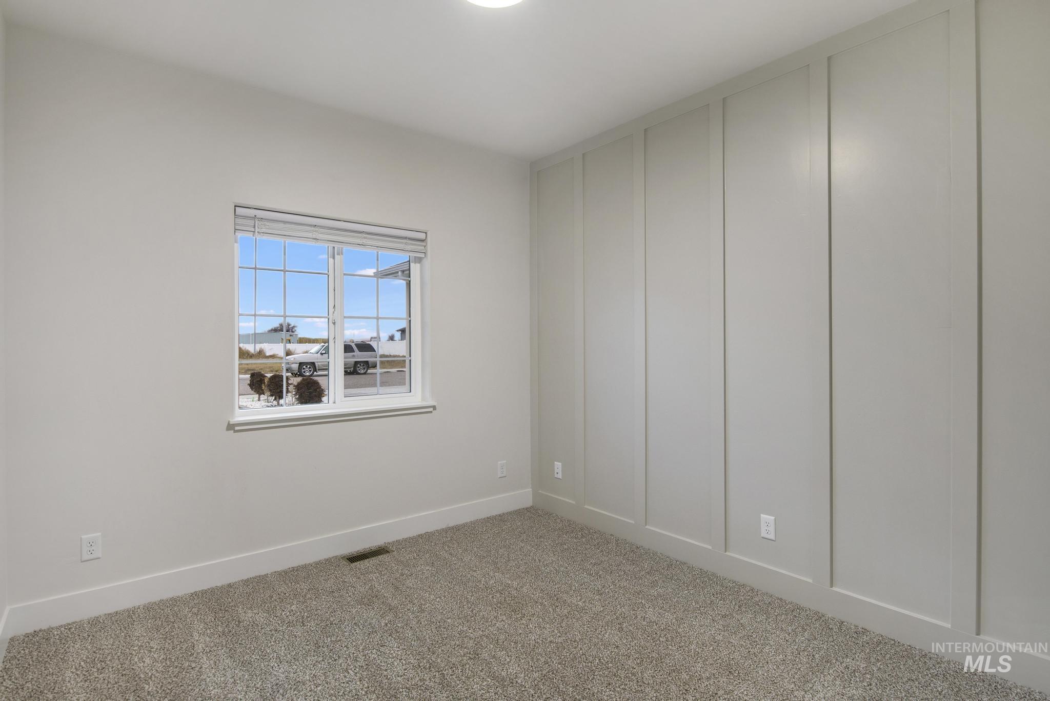 Carpeted empty room featuring a decorative wall