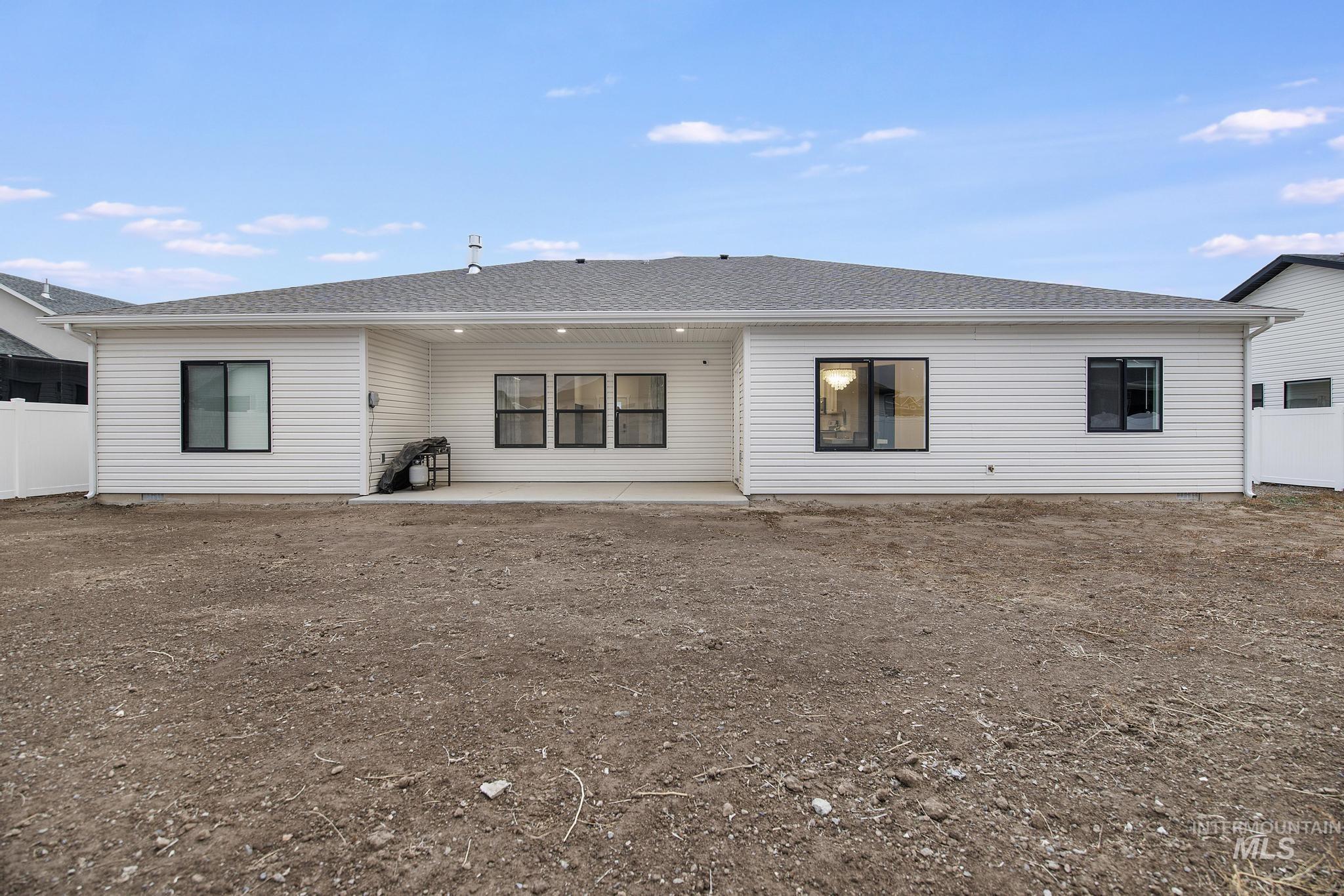 Rear view of house with a patio and a shingled roof