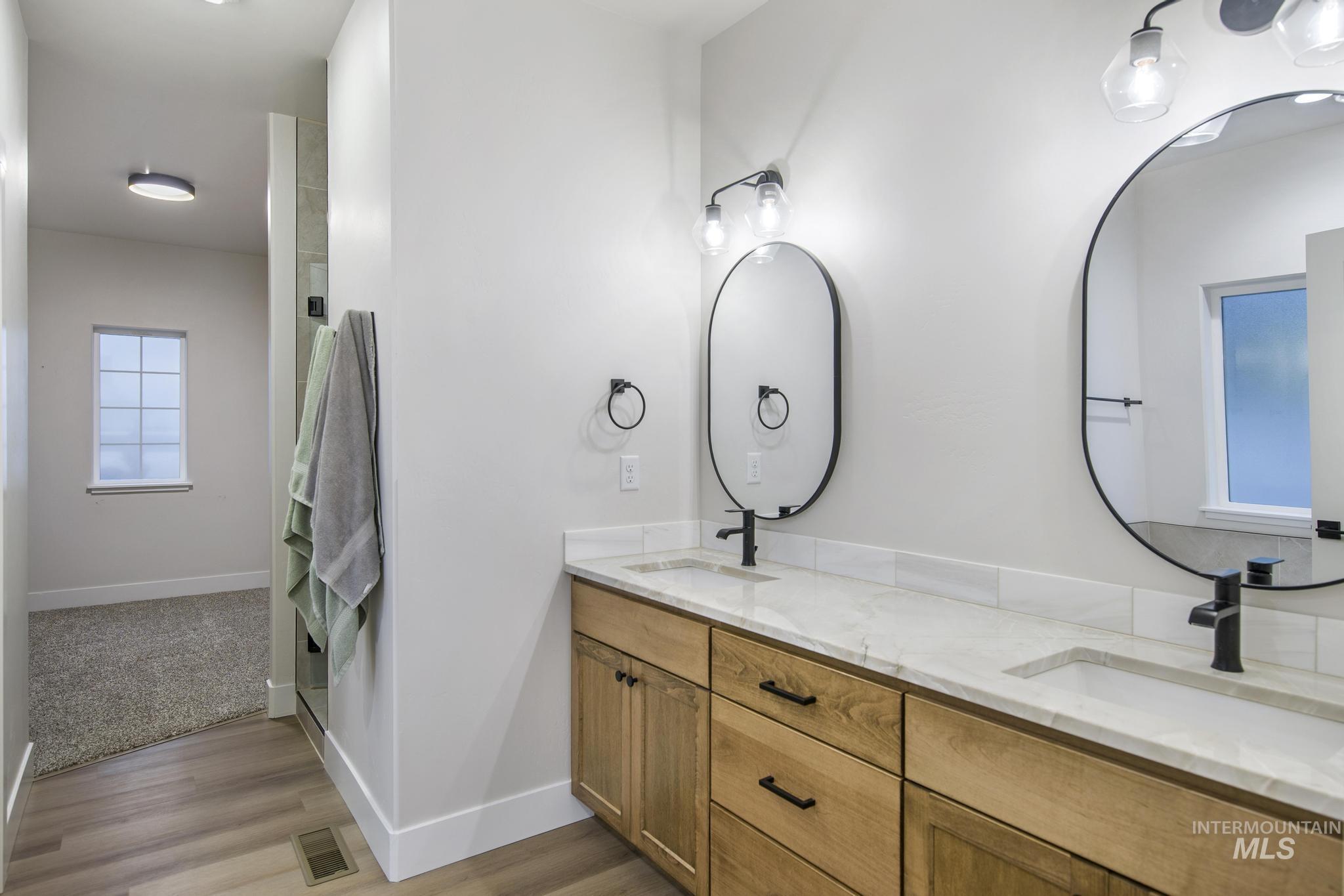 Bathroom with double vanity and light wood-style flooring