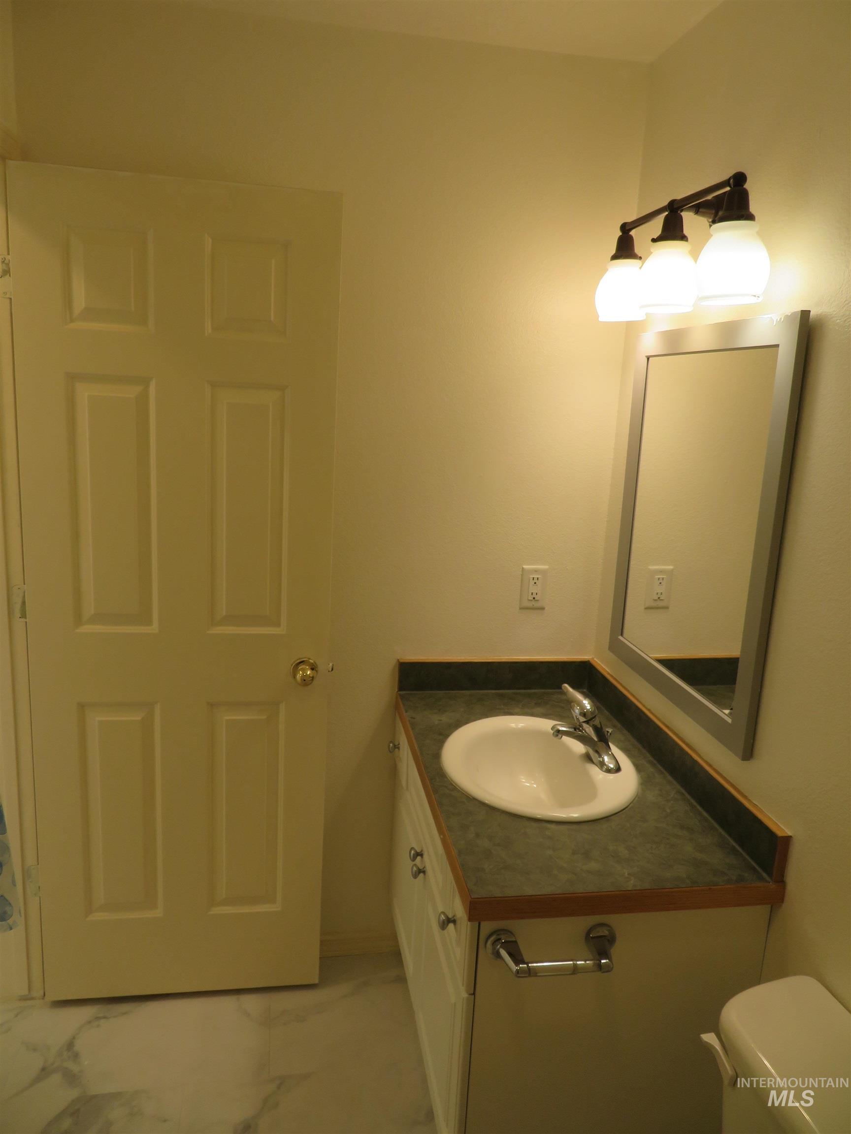 Half bathroom featuring light marble finish flooring and vanity