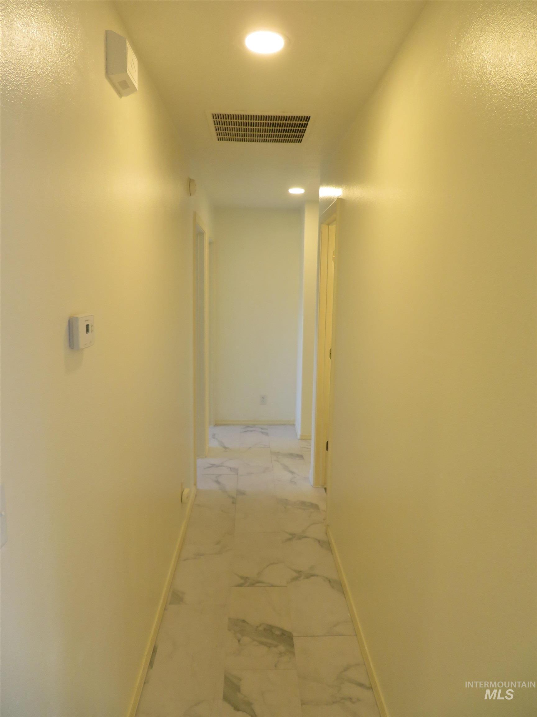 Hall featuring recessed lighting and light marble finish floors