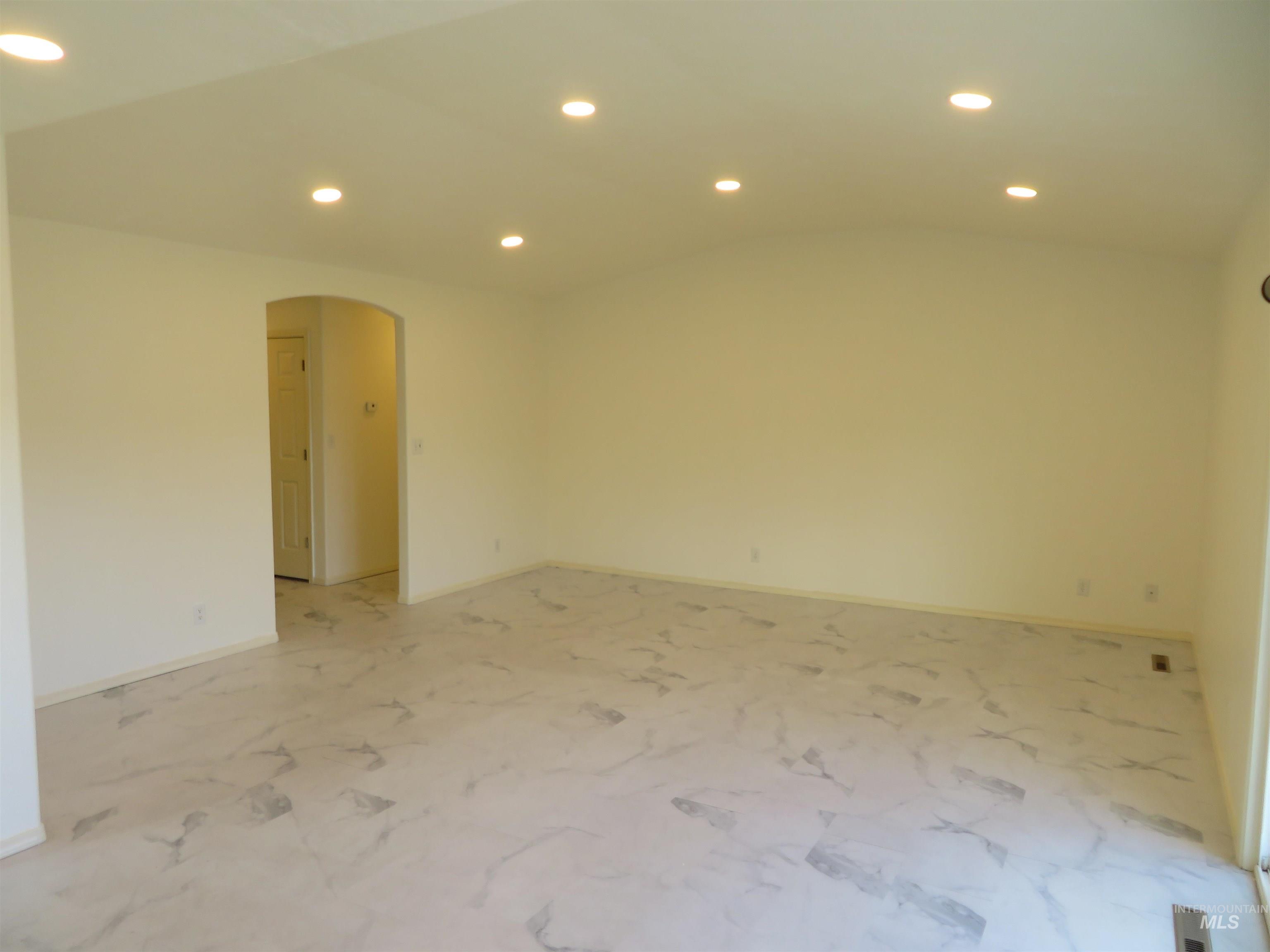 Unfurnished room featuring recessed lighting, arched walkways, and vaulted ceiling