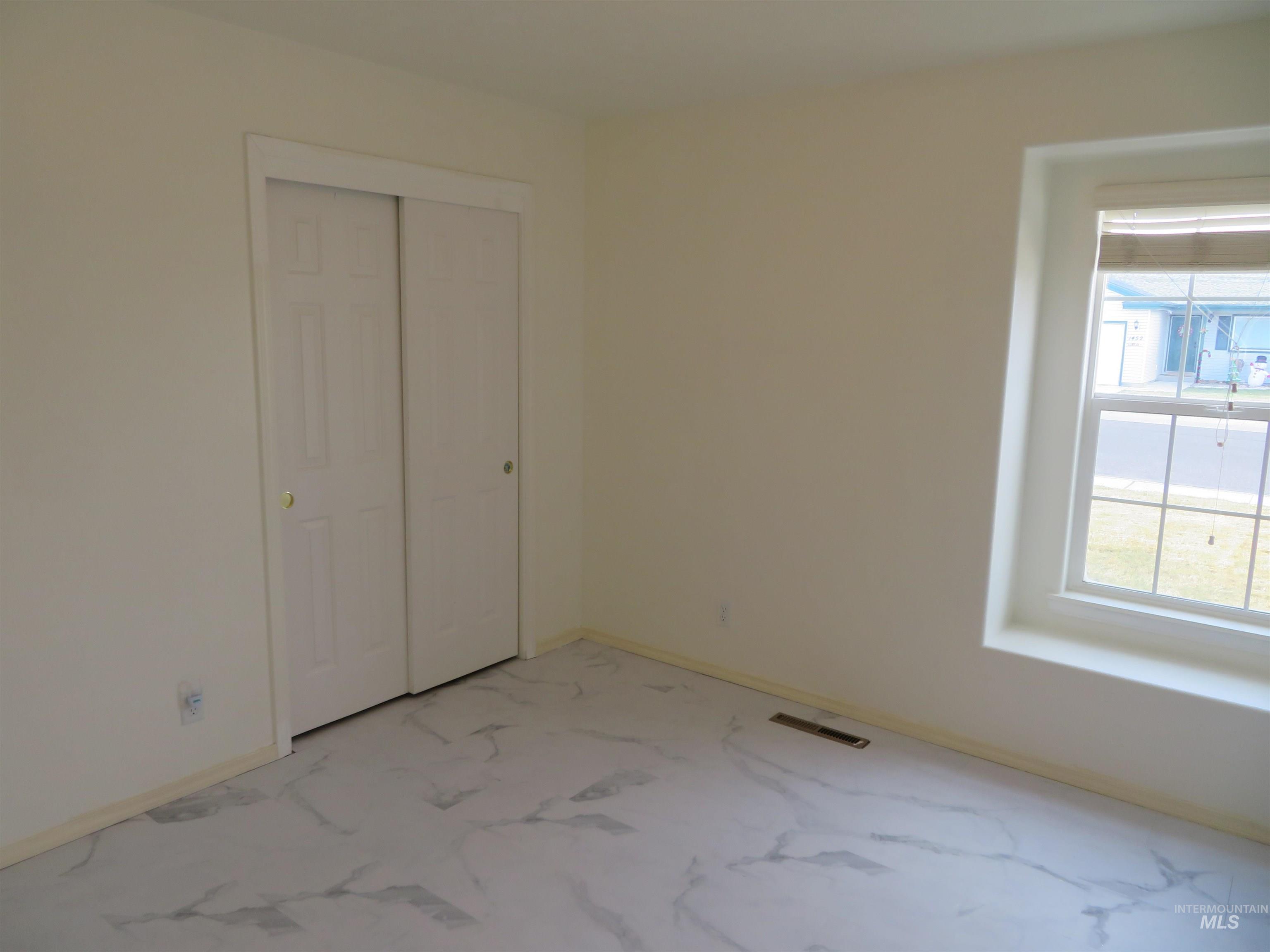 Unfurnished bedroom with a closet and light marble finish floors