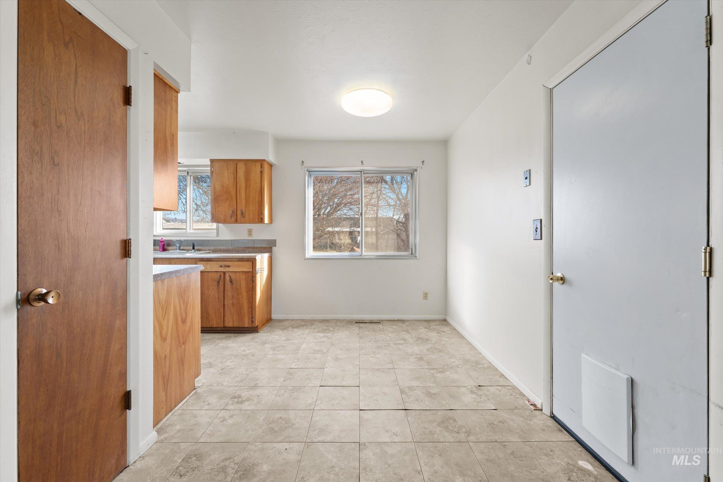 Kitchen featuring brown cabinetry, light countertops, and light tile patterned floors
