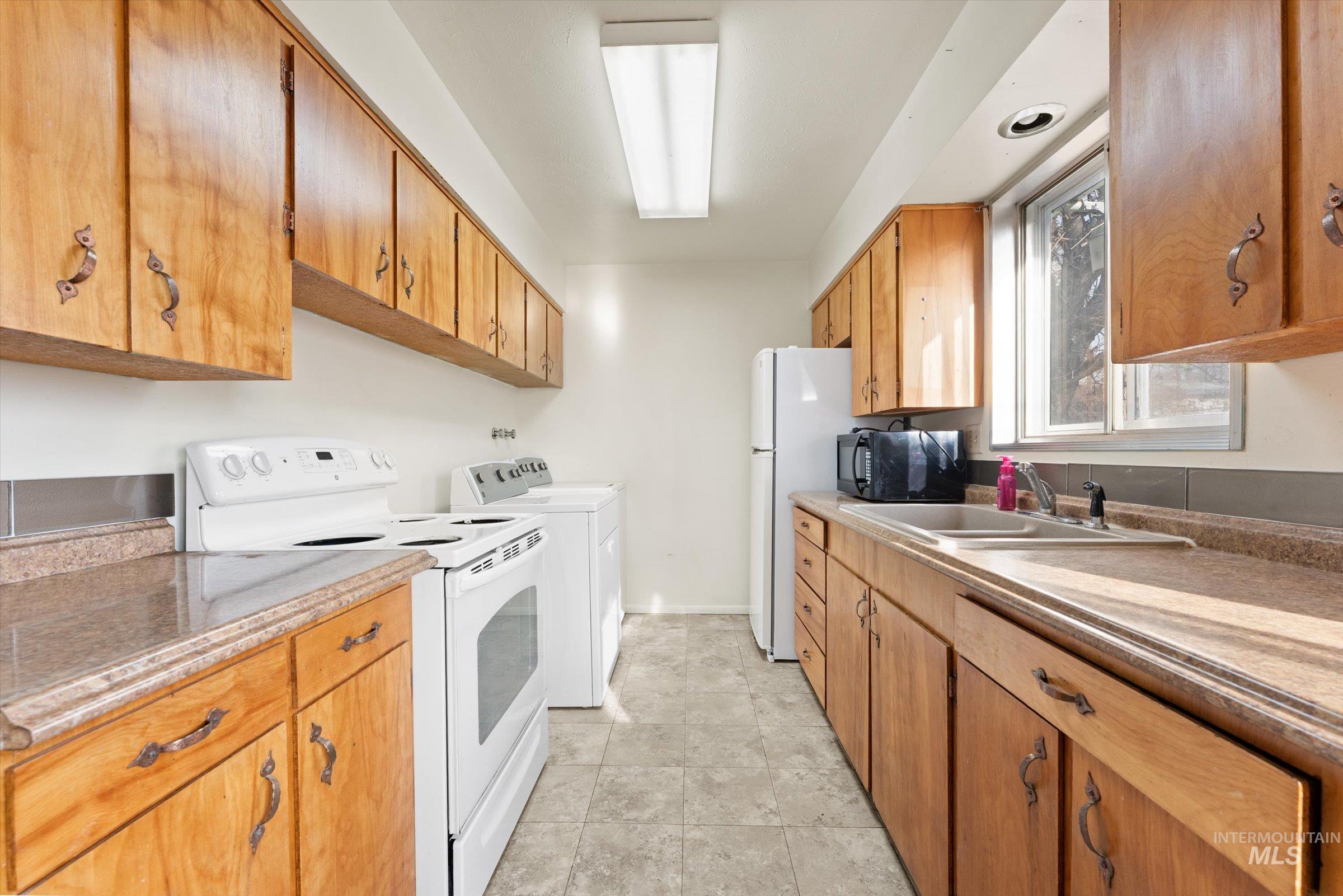 Kitchen featuring electric stove, black microwave, and brown cabinets