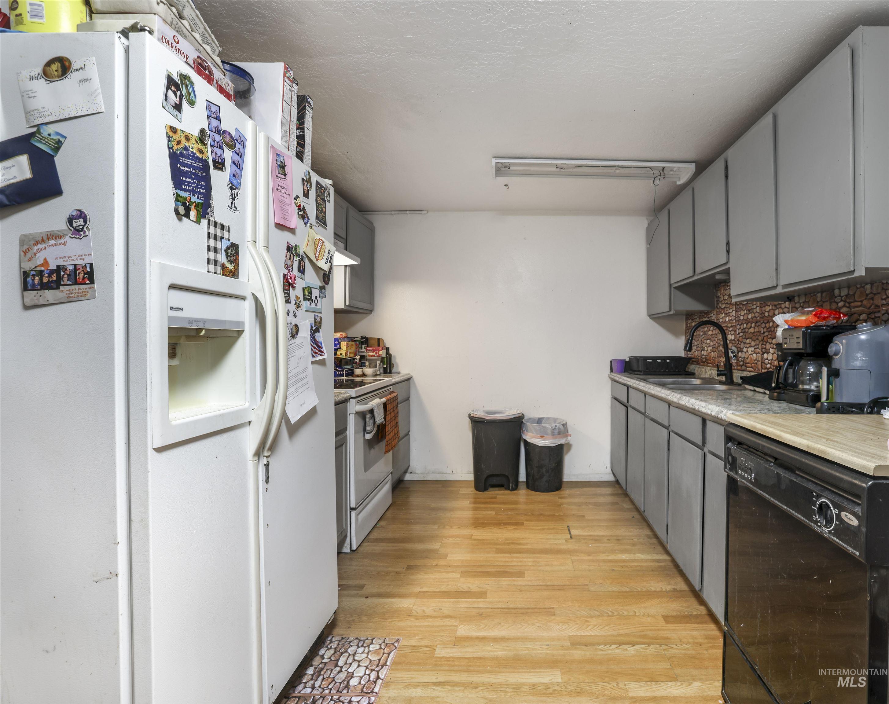 Kitchen featuring white appliances, gray cabinetry, light wood-style floors, light countertops, and a textured ceiling