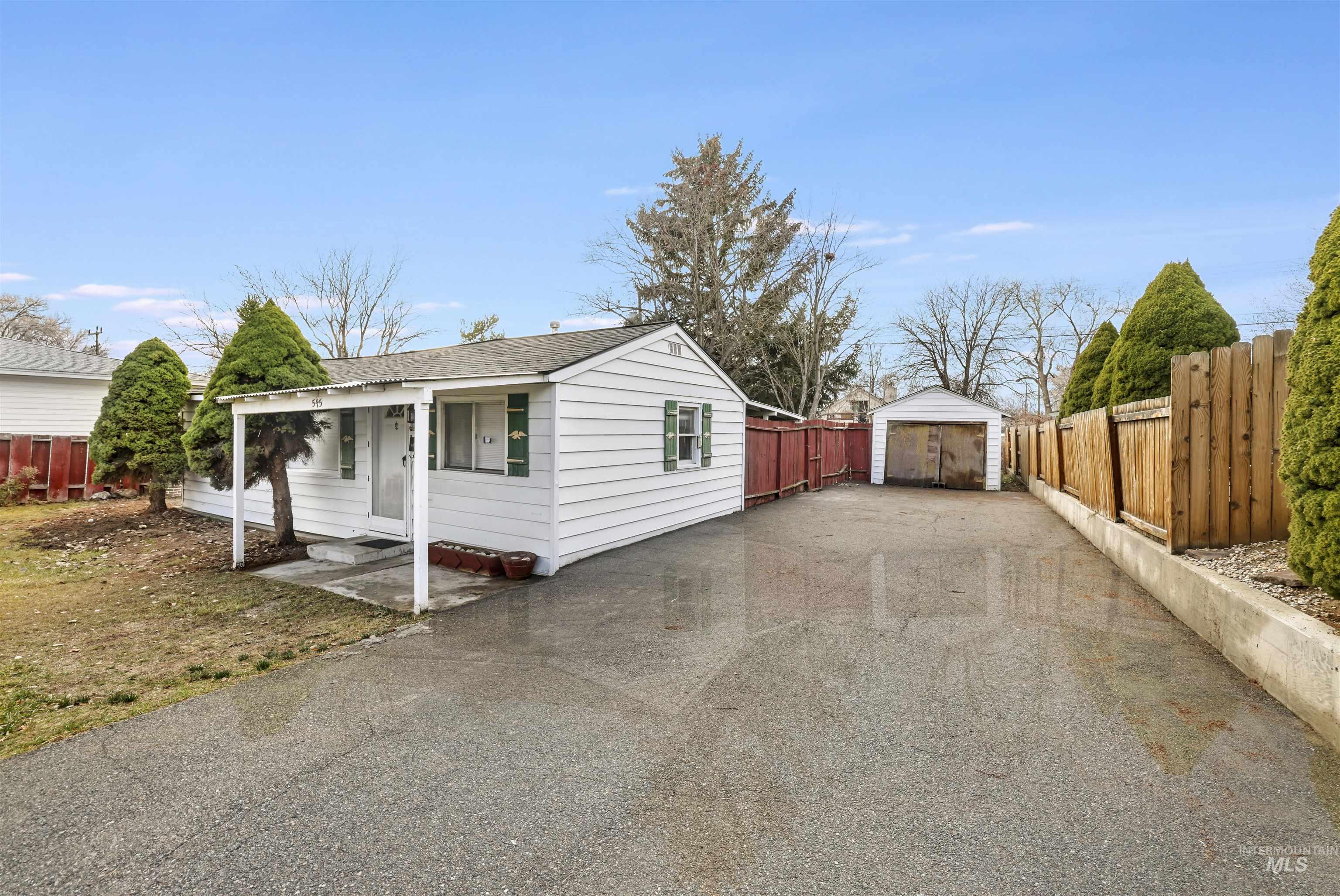 View of property exterior featuring a shingled roof, driveway, an outdoor structure, and a detached garage