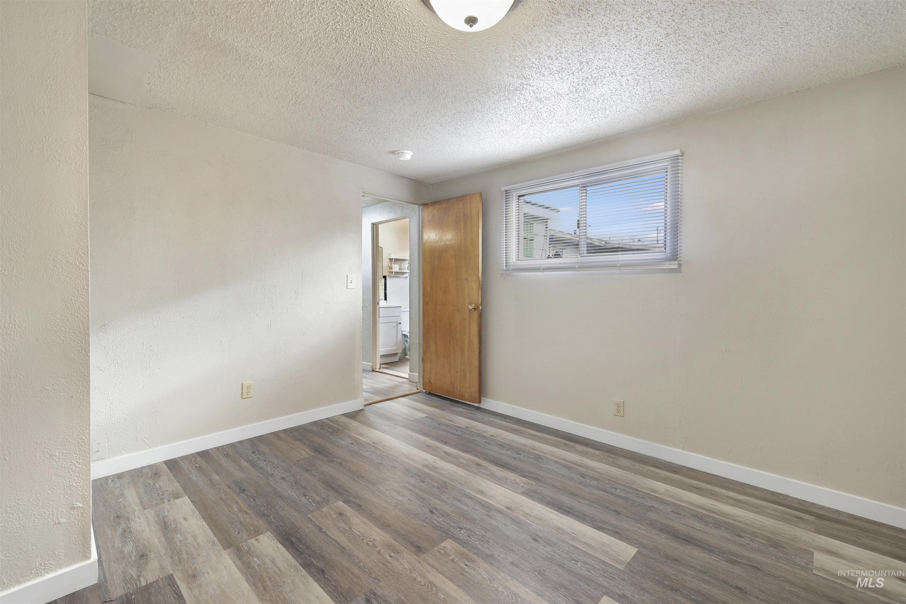 Spare room featuring wood finished floors, a textured ceiling, and a textured wall