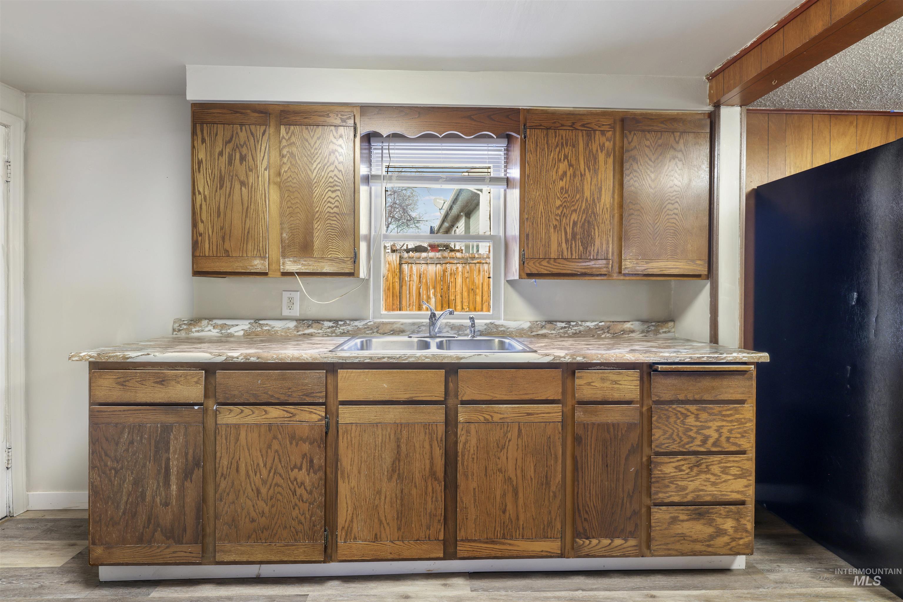 Kitchen featuring freestanding refrigerator, brown cabinets, light countertops, and light wood-style flooring