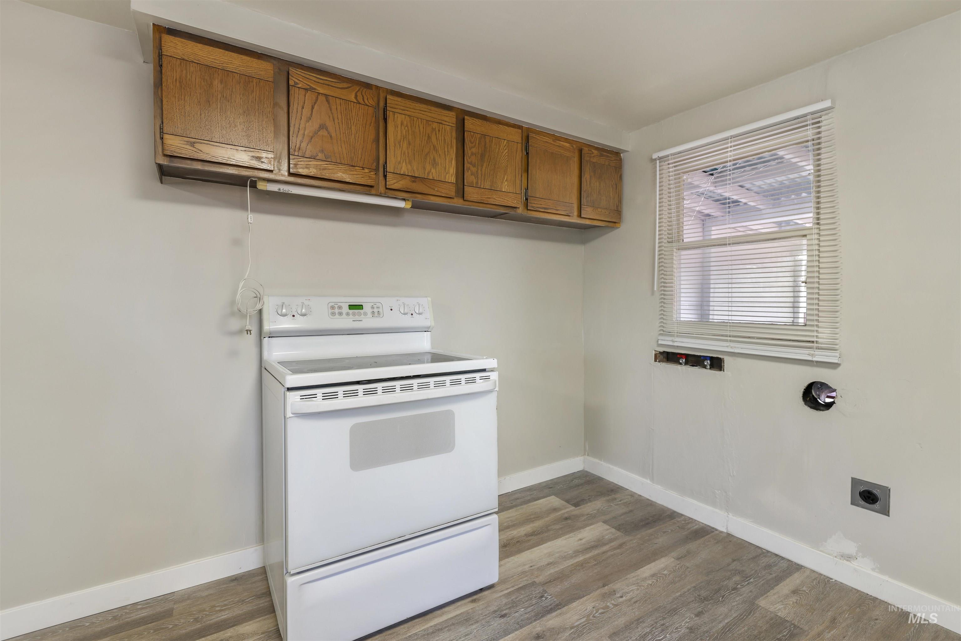 Kitchen featuring electric range, brown cabinets, and light wood-style flooring