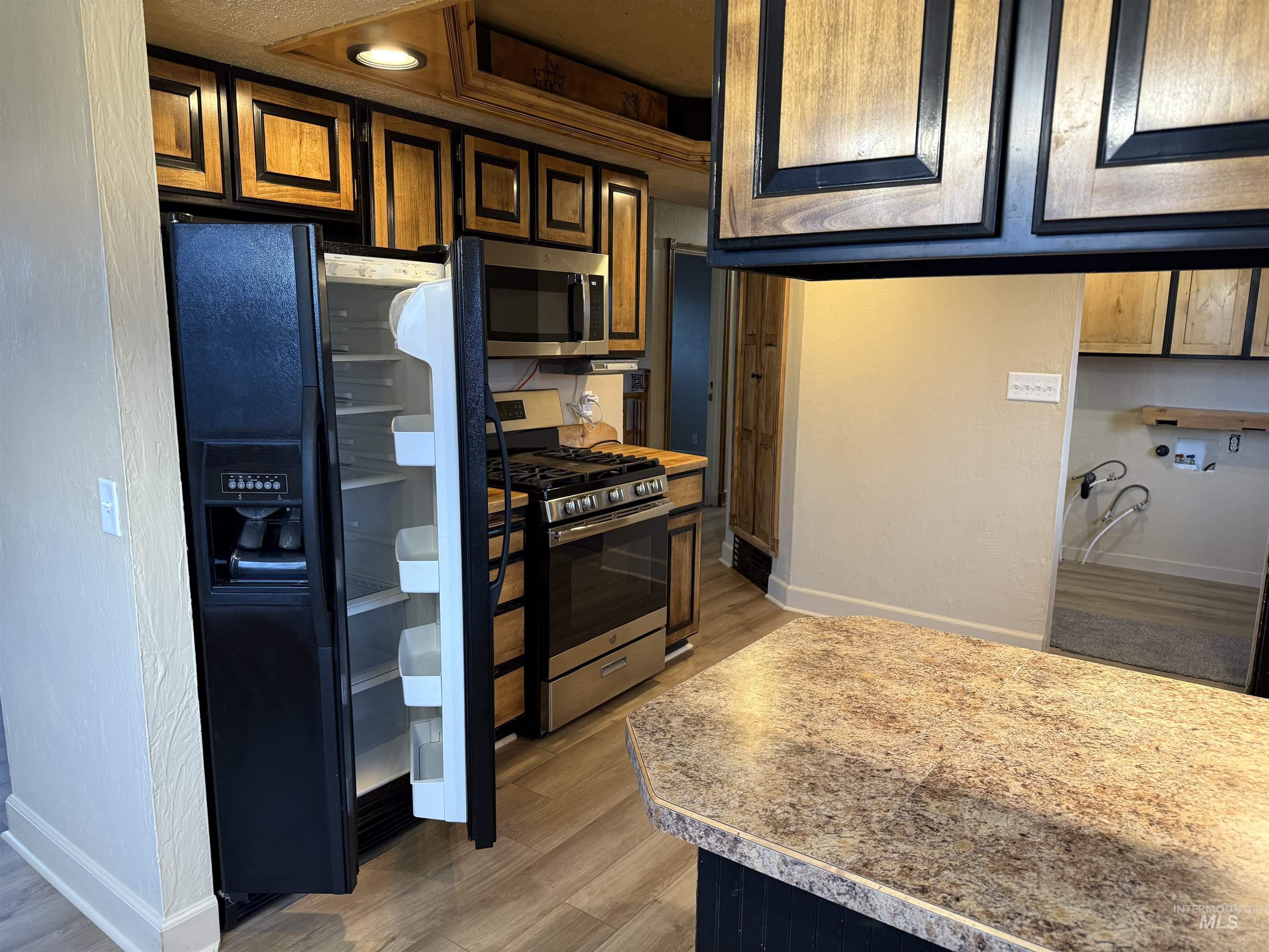 Kitchen featuring appliances with stainless steel finishes, light countertops, and light wood-style floors