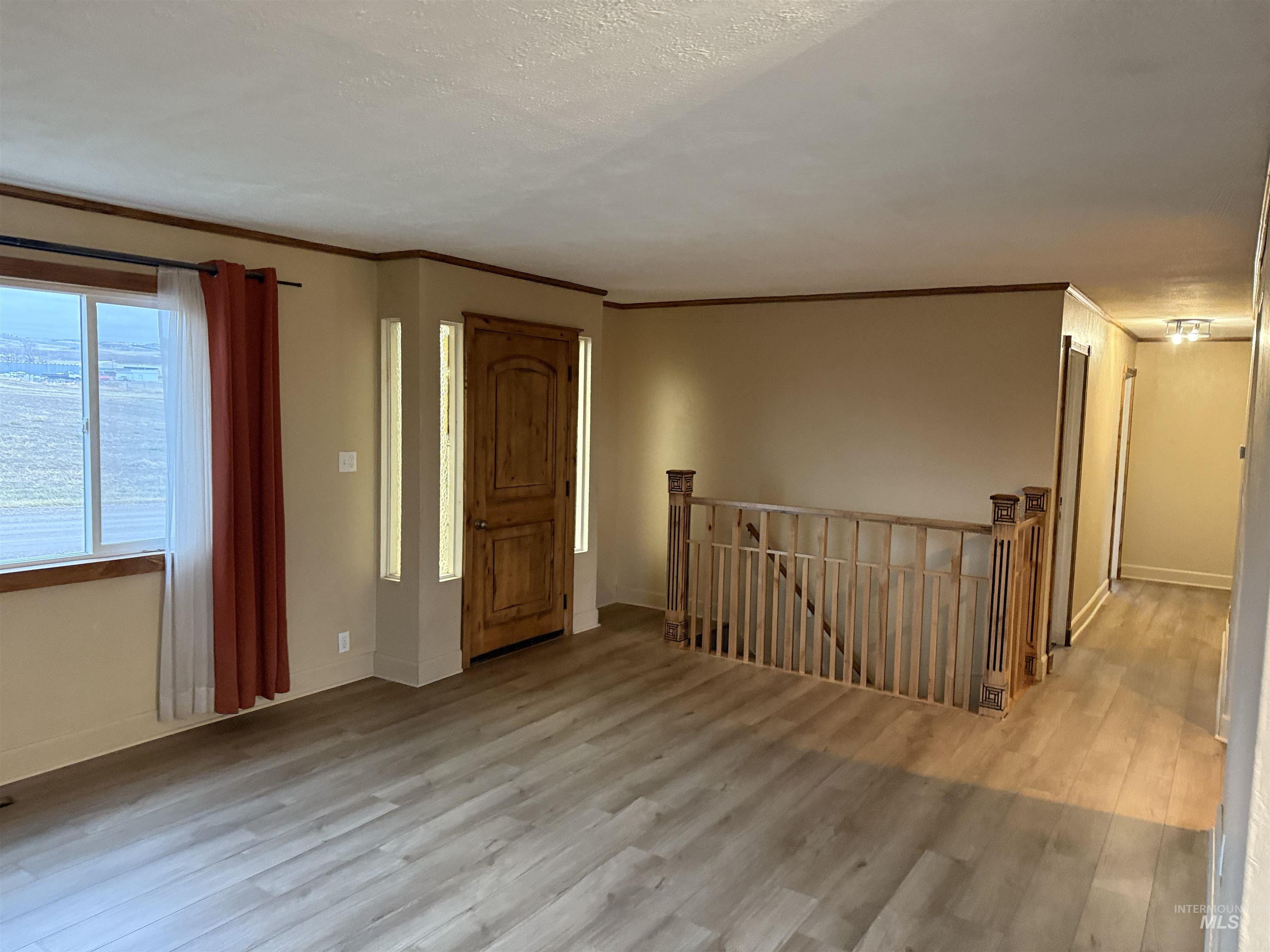 Entrance foyer with light wood finished floors, ornamental molding, and a textured ceiling
