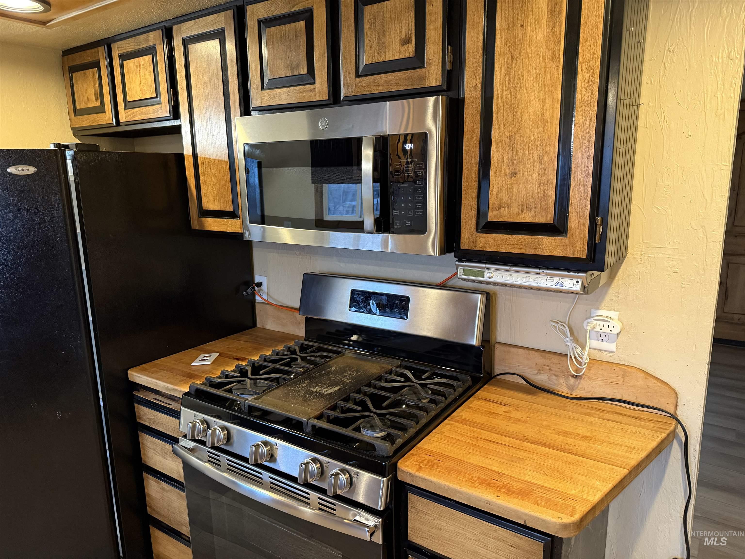 Kitchen featuring appliances with stainless steel finishes, light countertops, and a textured wall