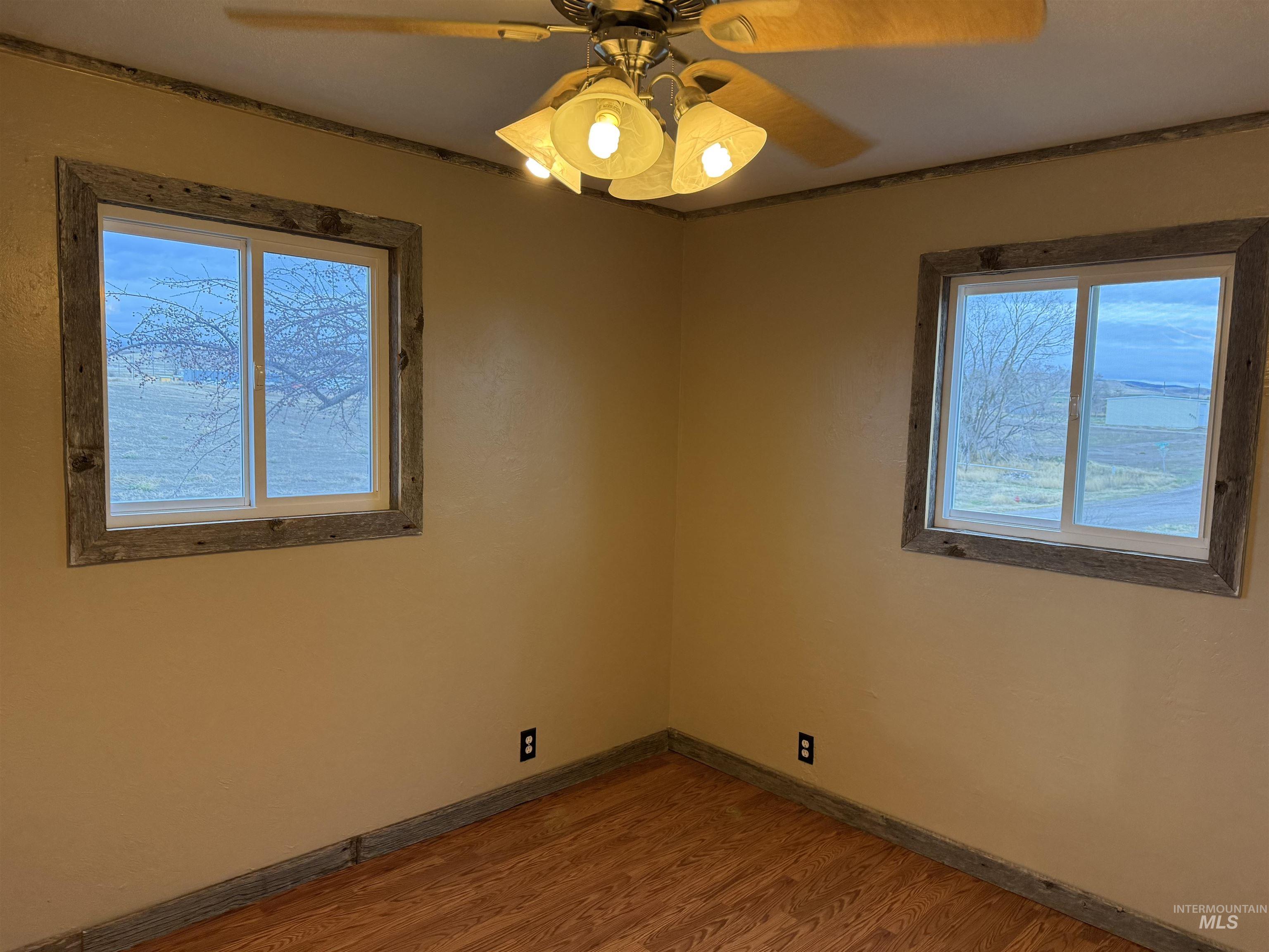 Unfurnished room featuring a ceiling fan, wood finished floors, and healthy amount of natural light