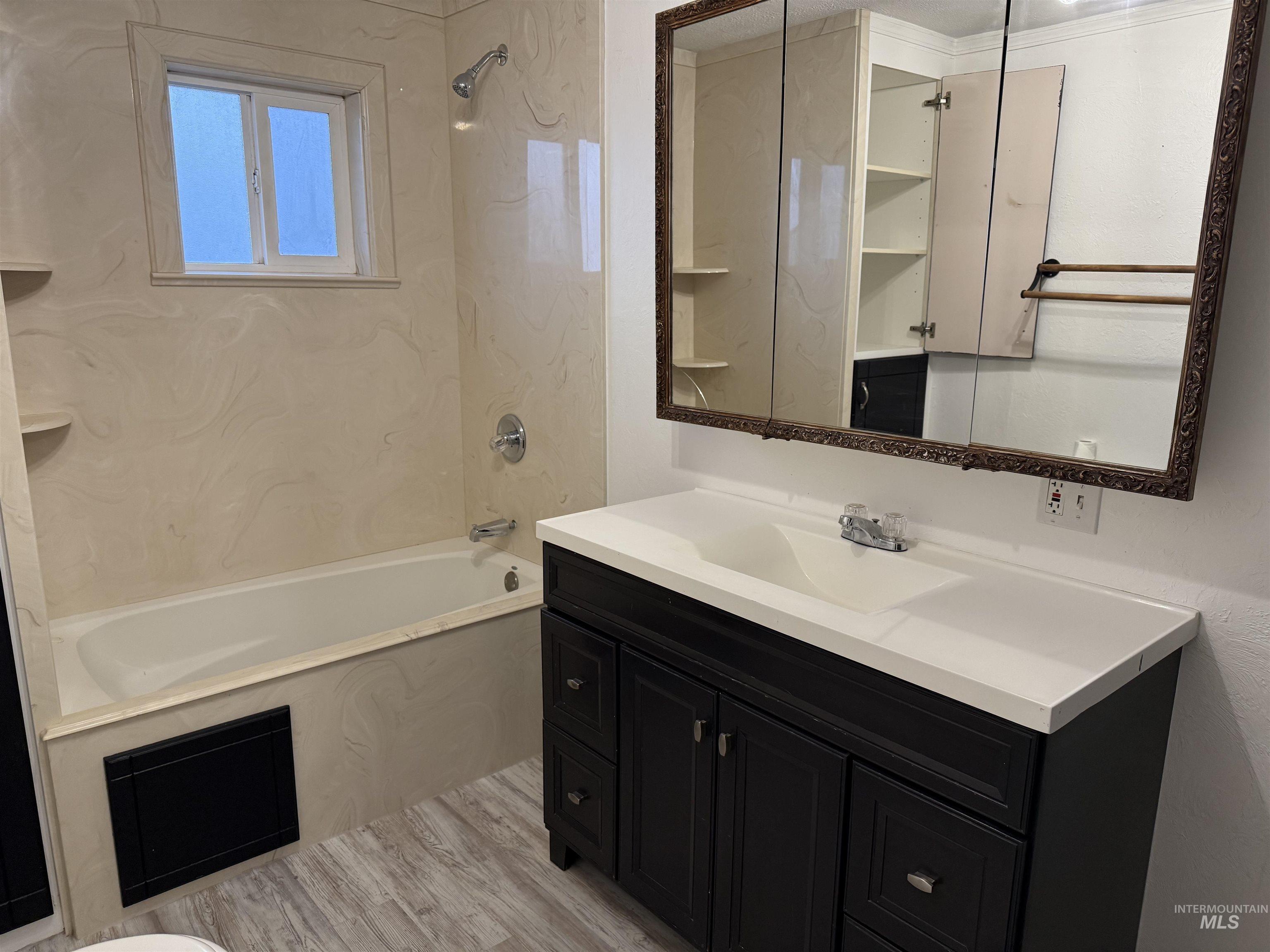 Full bath with shower / tub combination, vanity, and light wood-type flooring