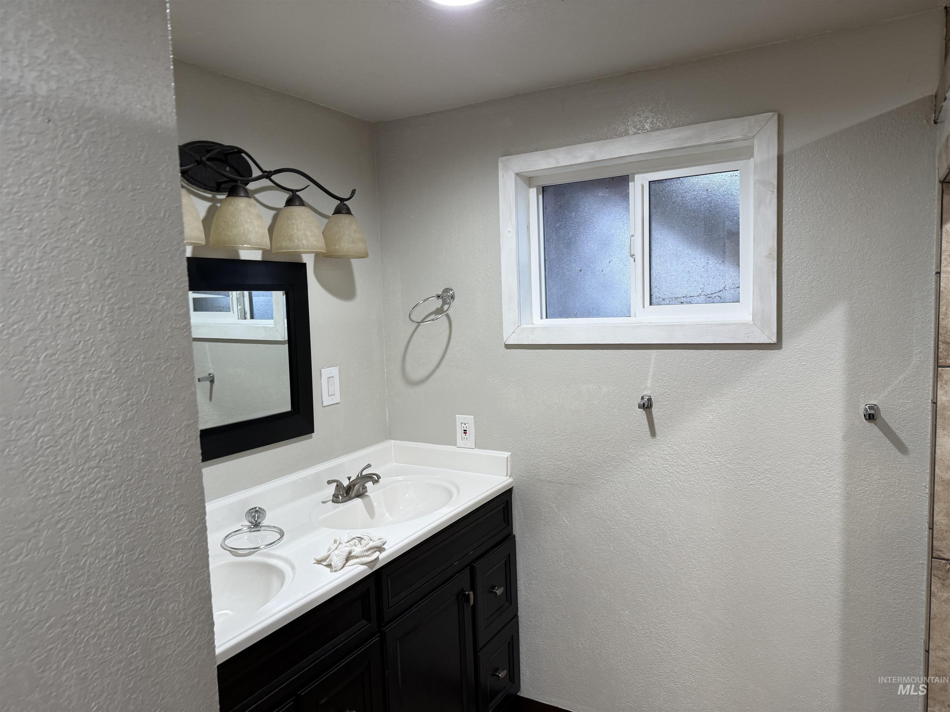Full bathroom featuring a textured wall and double vanity