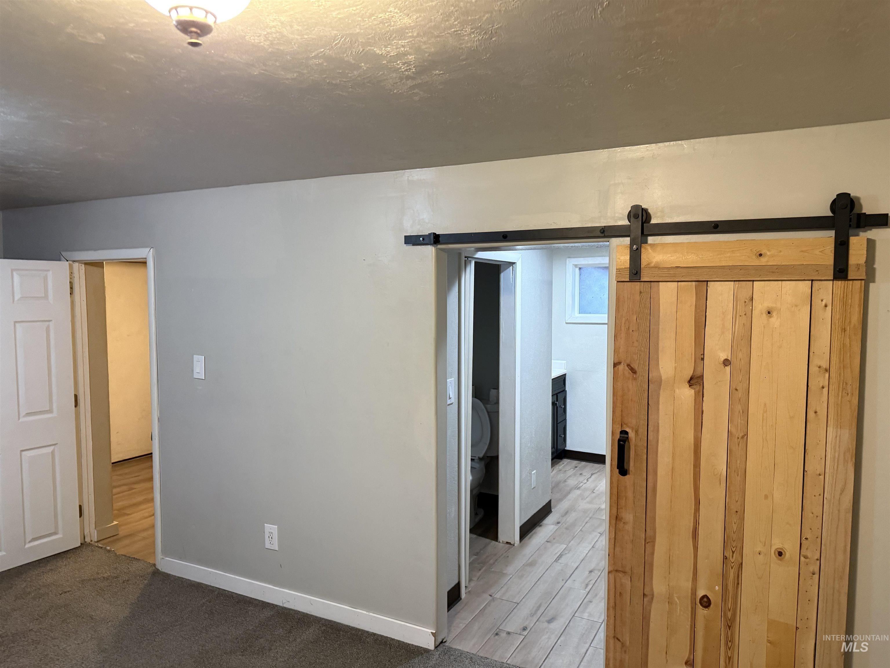 Unfurnished room with a barn door, wood finished floors, and a textured ceiling
