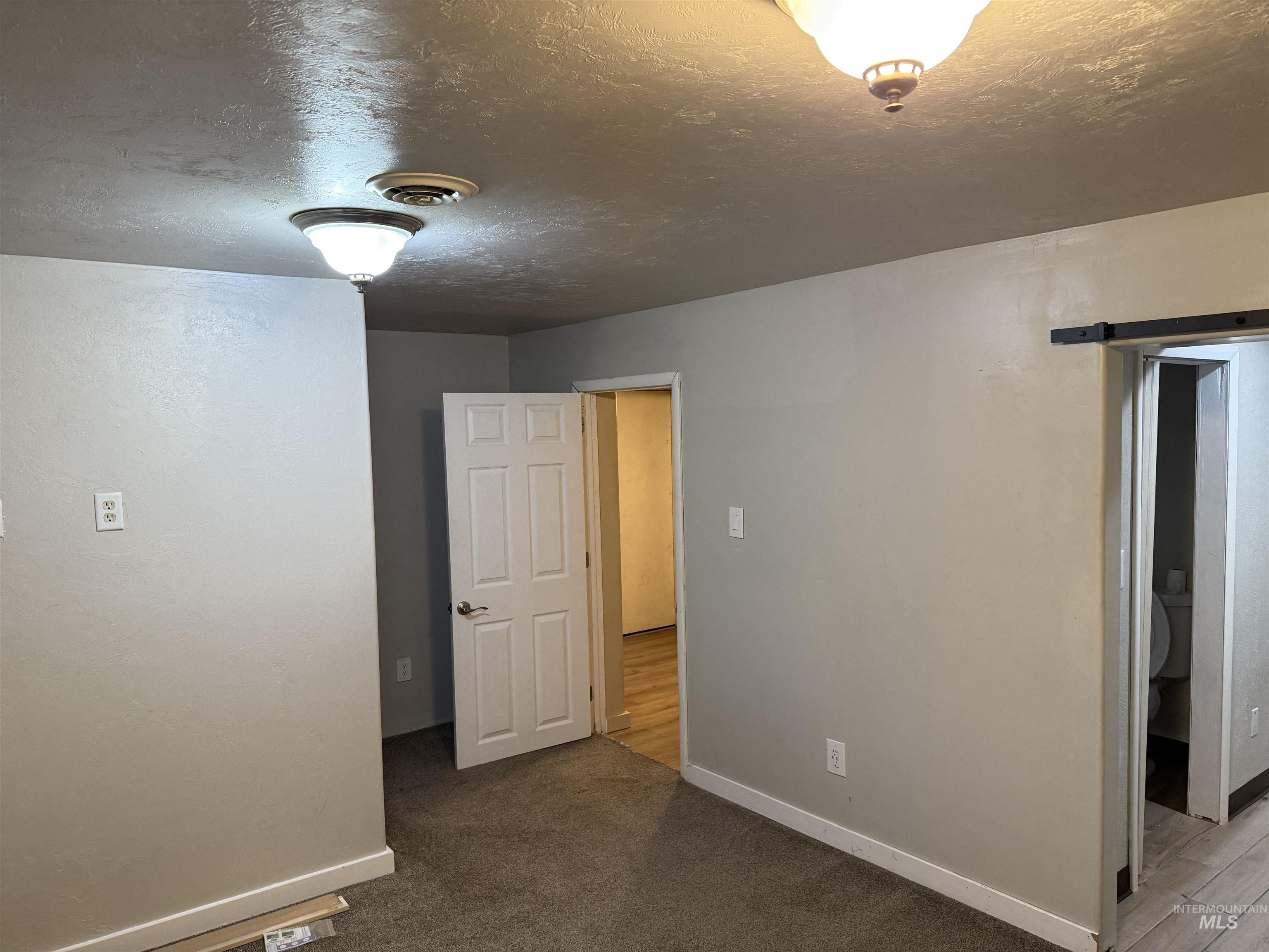 Empty room featuring a textured ceiling and dark colored carpet