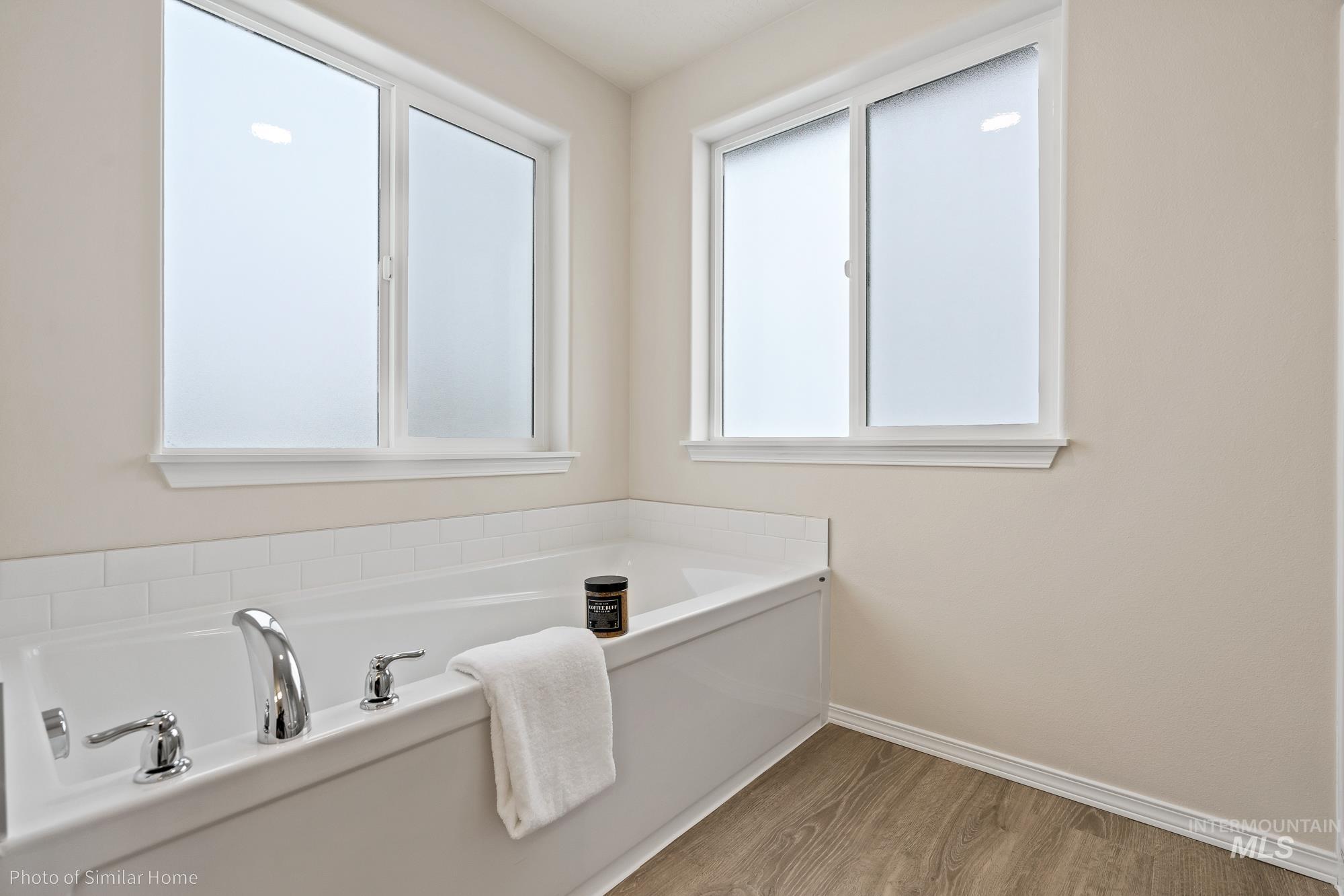 Full bath with a garden tub and light wood-style flooring