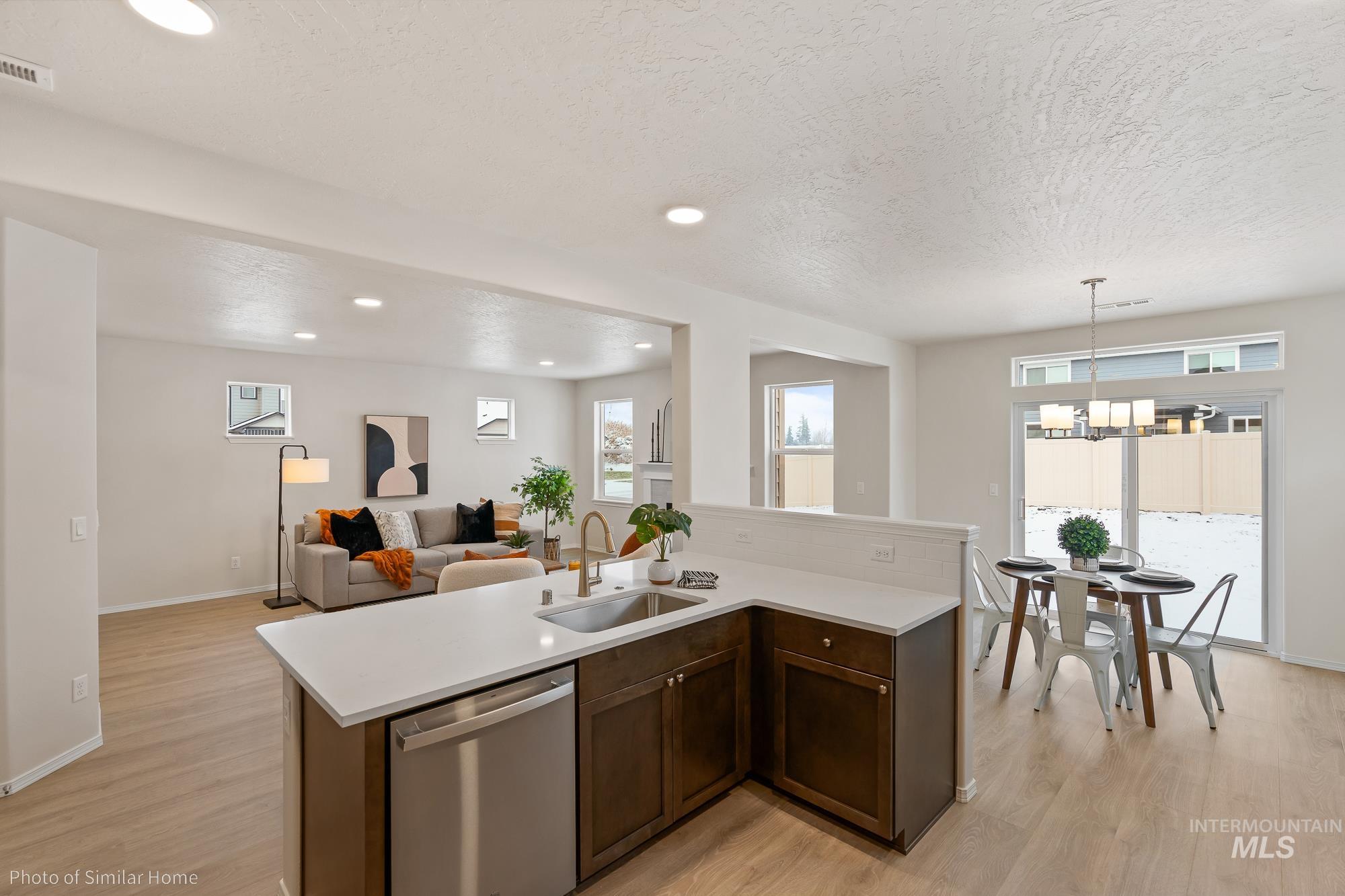 Kitchen with dark brown cabinets, stainless steel dishwasher, recessed lighting, light wood-type flooring, and hanging light fixtures